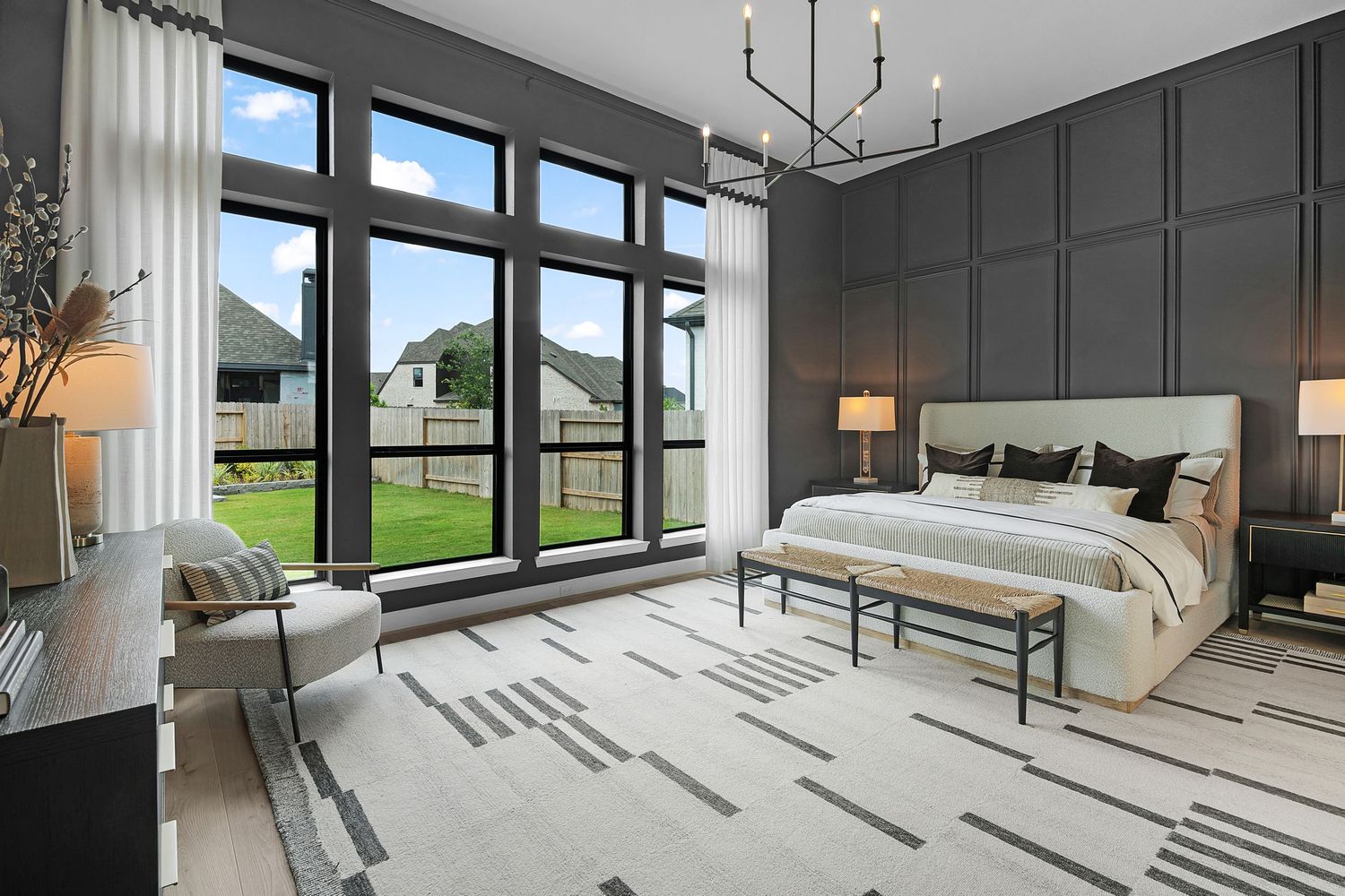 Modern bedroom interior with gray walls, white bedding, and large windows offering natural light and outdoor views.