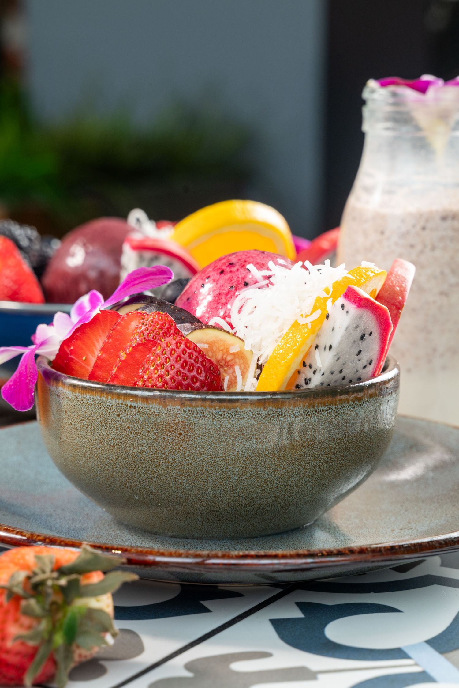 Fresh tropical fruit bowl filled with dragon fruit, strawberries, and citrus on a decorative plate.