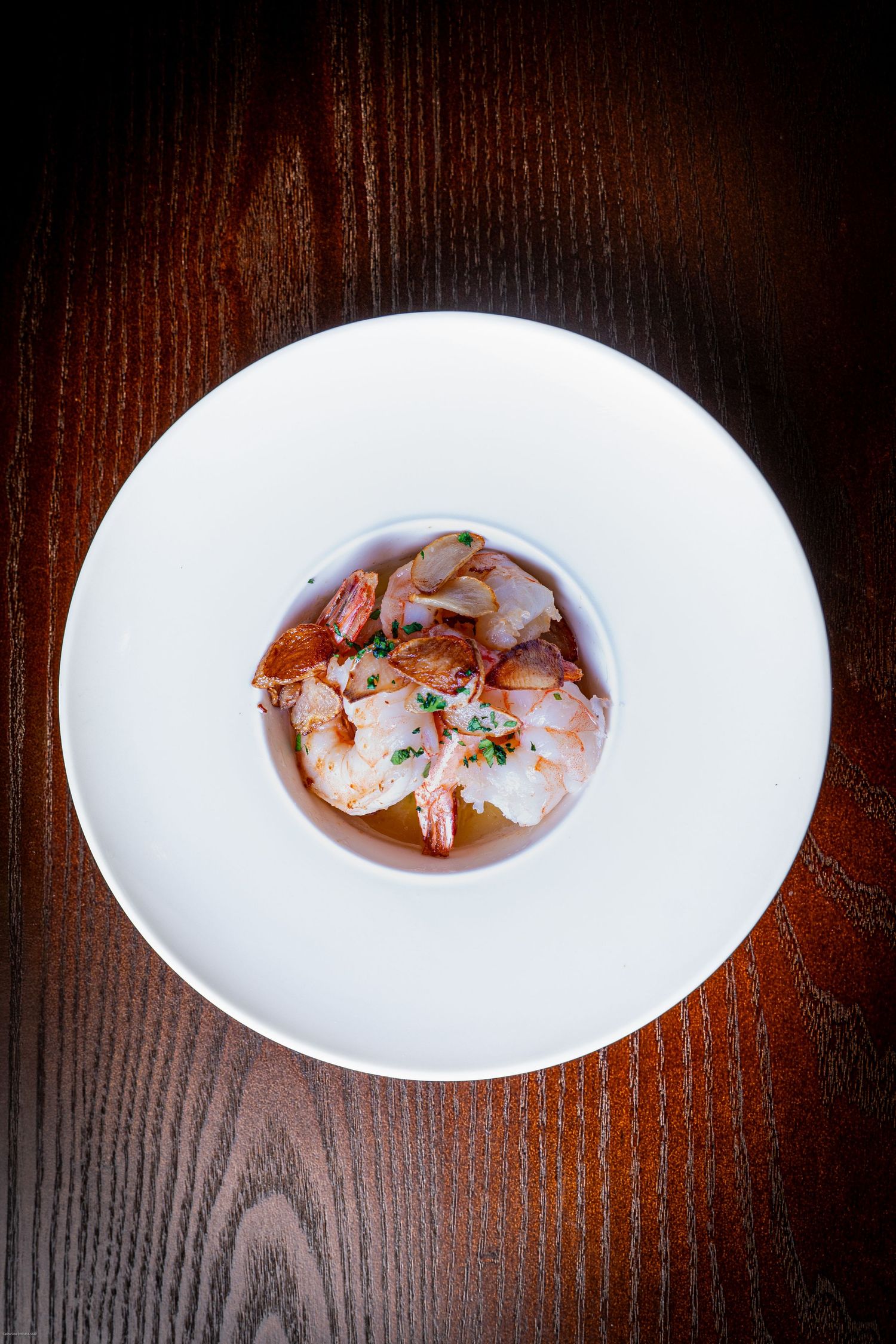 Elegantly plated shrimp in a minimalist presentation on a white circular dish.