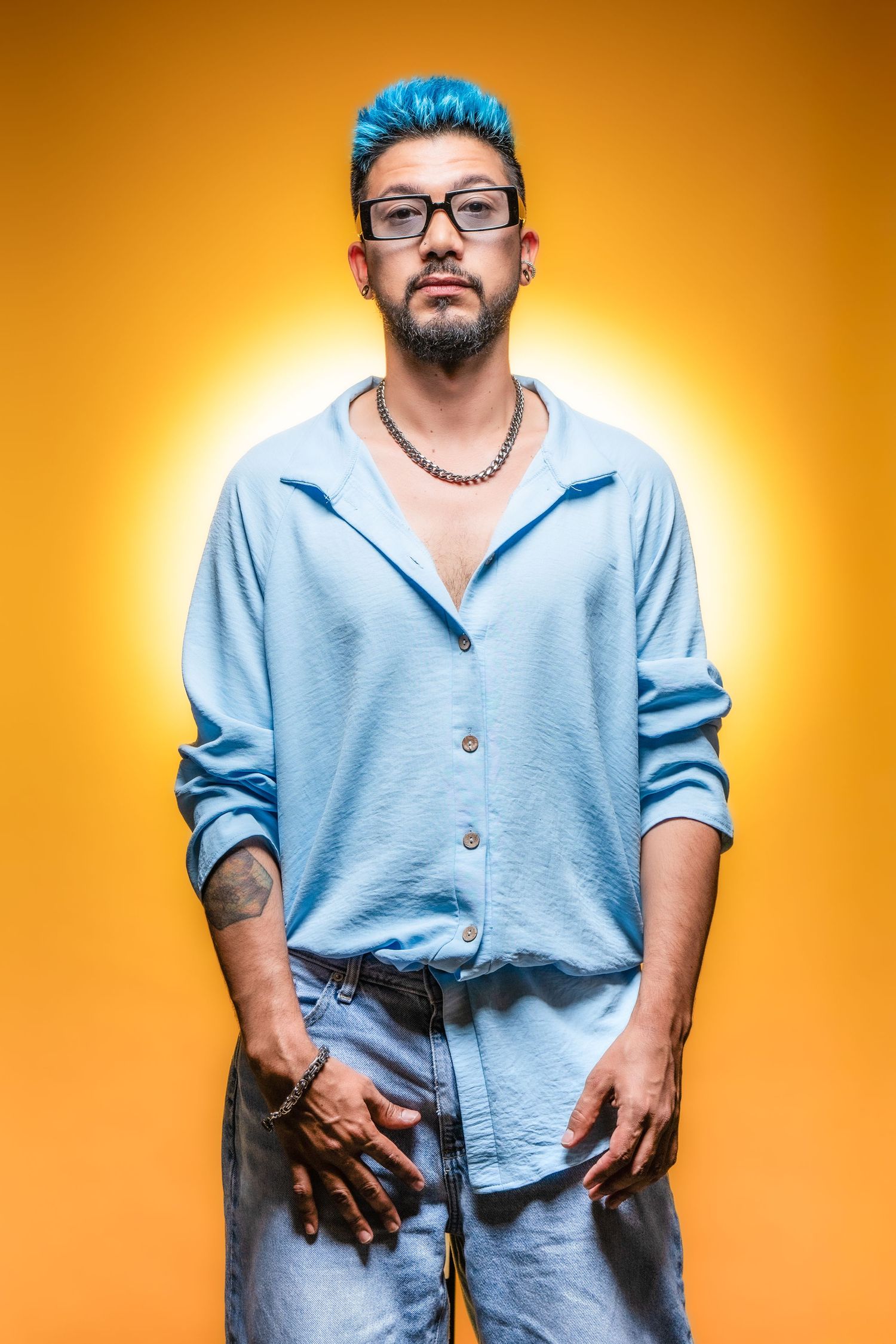 Creative portrait of a professional hairstylist in Houston, Texas, posing with a blow dryer and round brush on a vibrant yellow studio backg