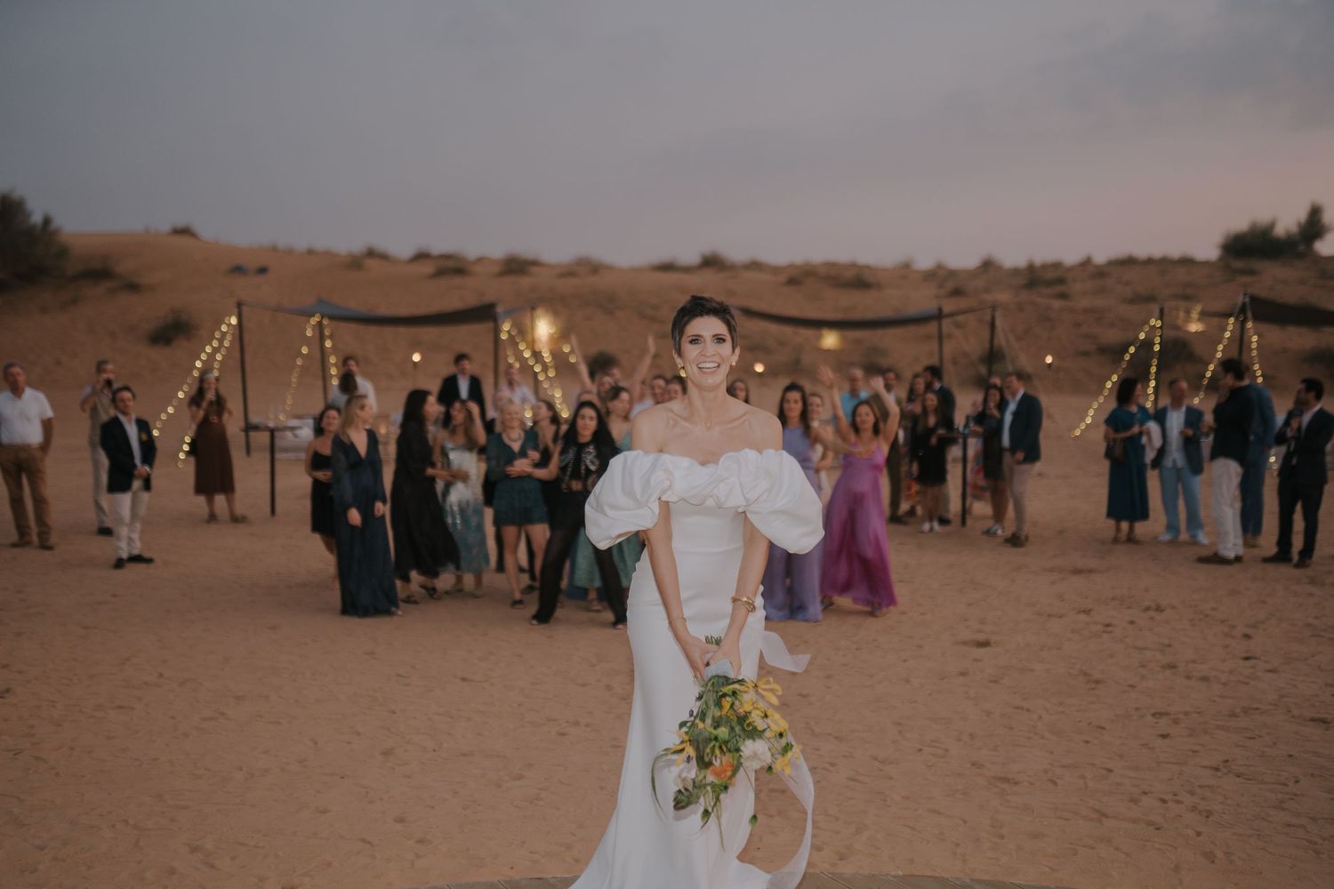 Desert wedding celebration with guests gathered around in a serene outdoor setting.