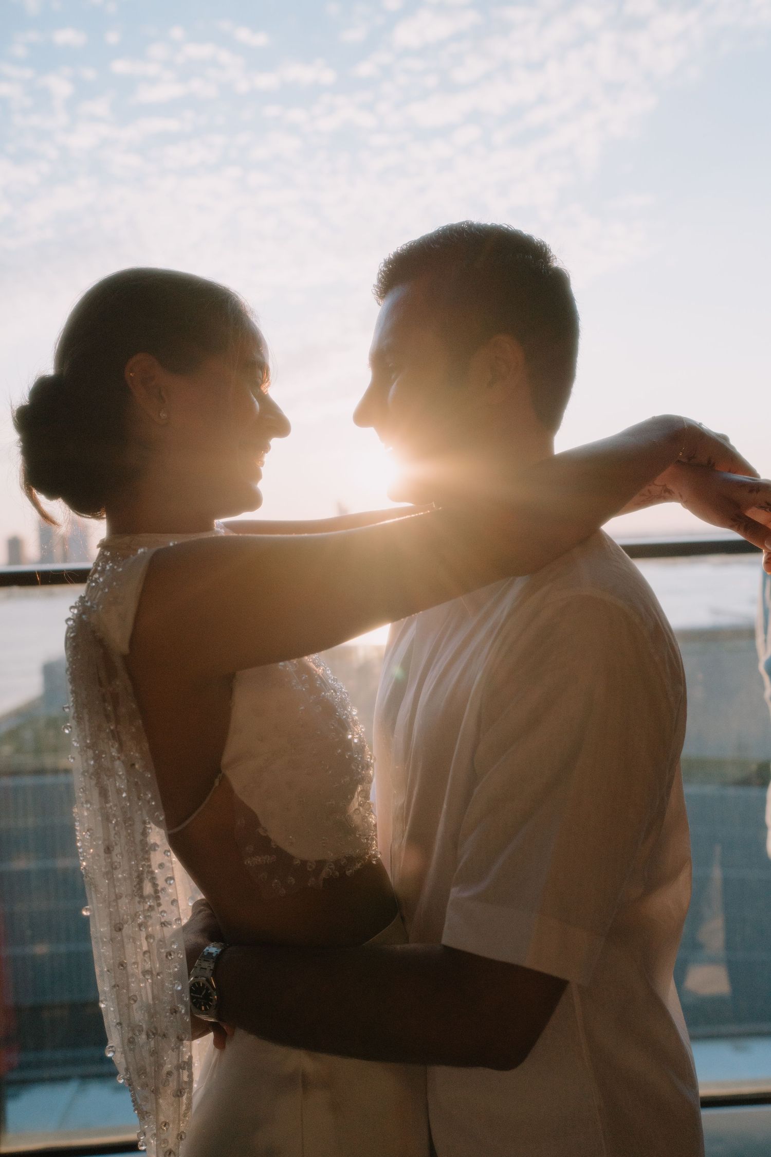 Romantic silhouette of a couple embracing during sunset on a balcony with soft glowing backlight.