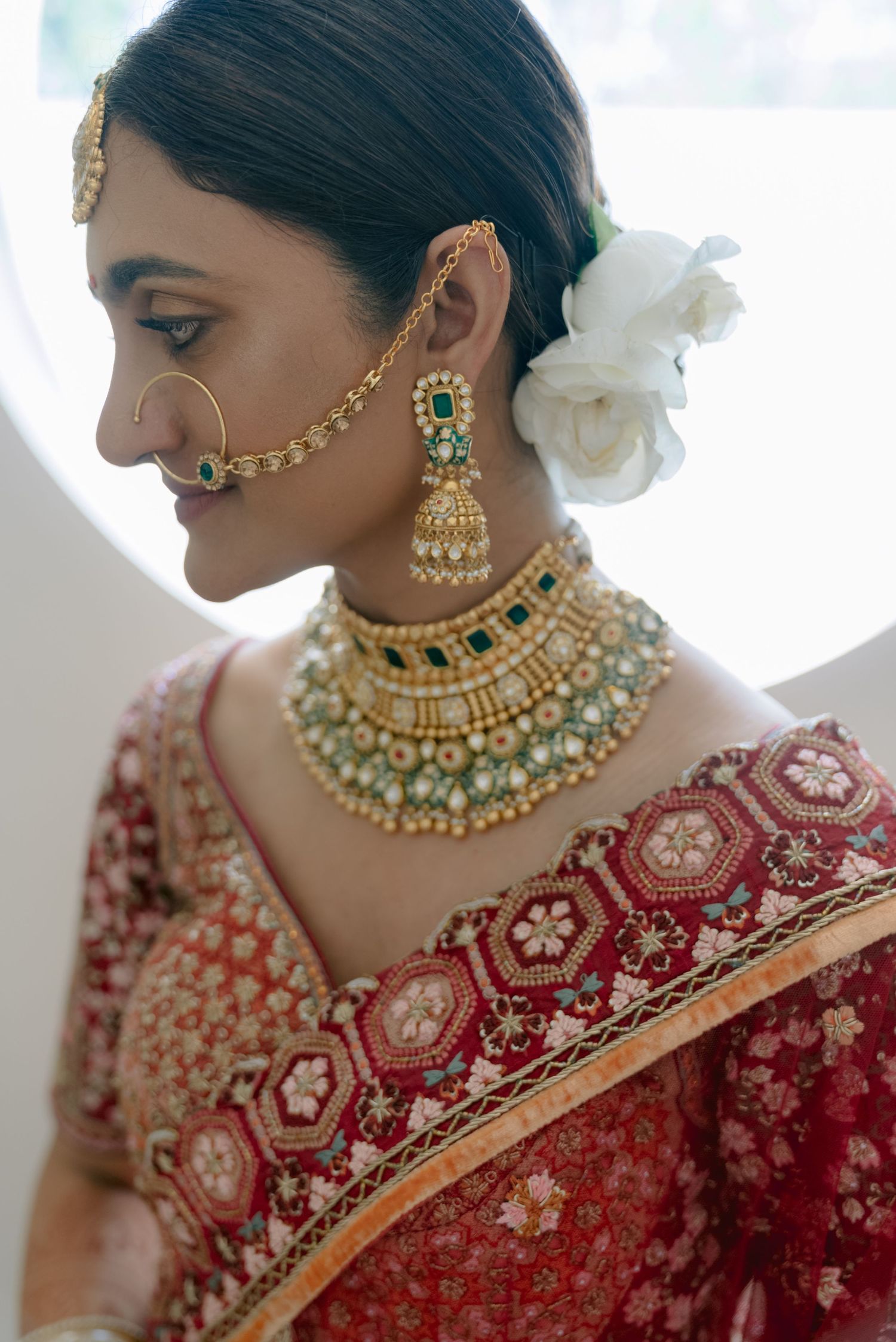 Detailed shot of traditional Indian bridal jewelry including nath and pearl-adorned choker necklace.