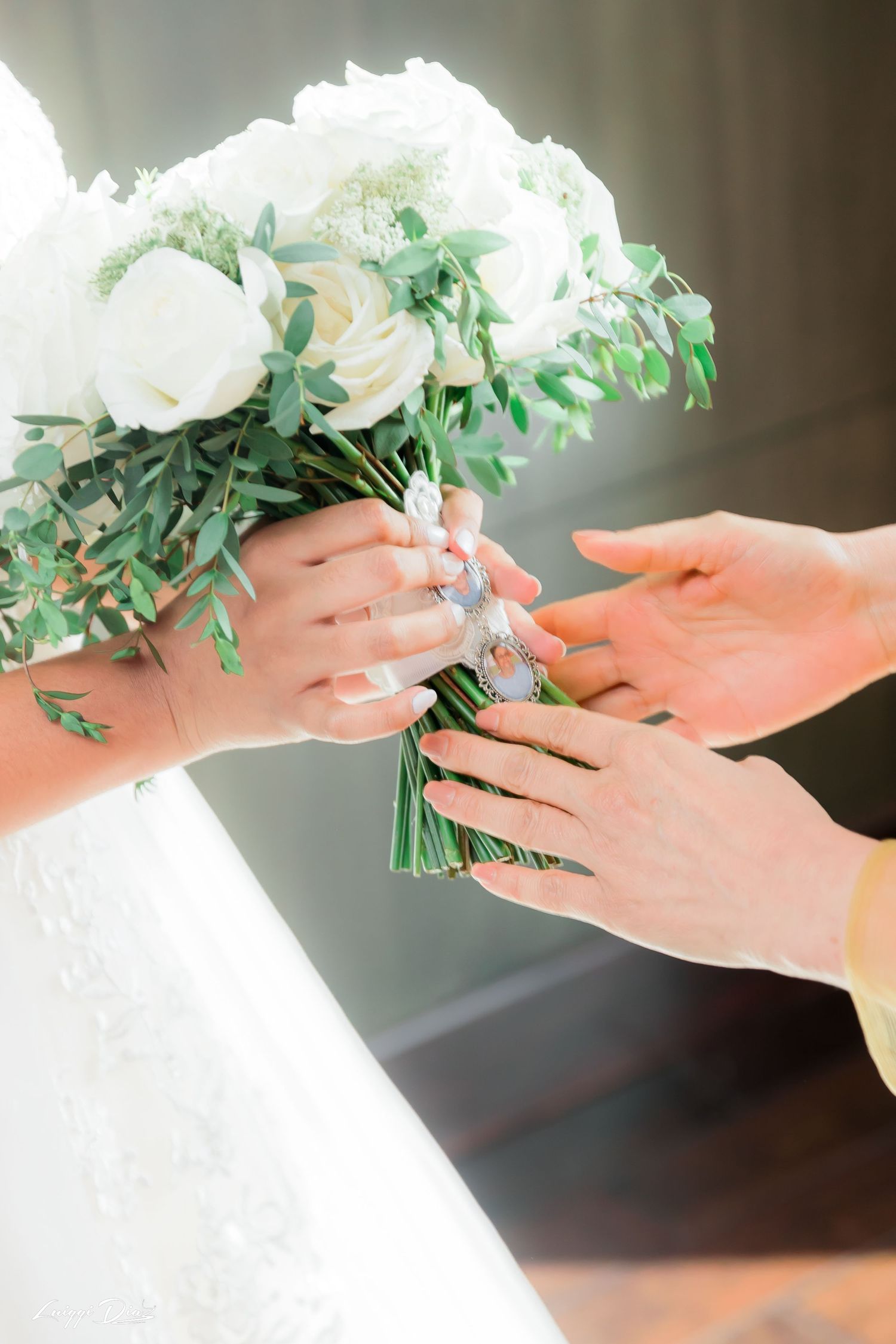 Close-up of hands exchanging white and green floral wedding bouquet.