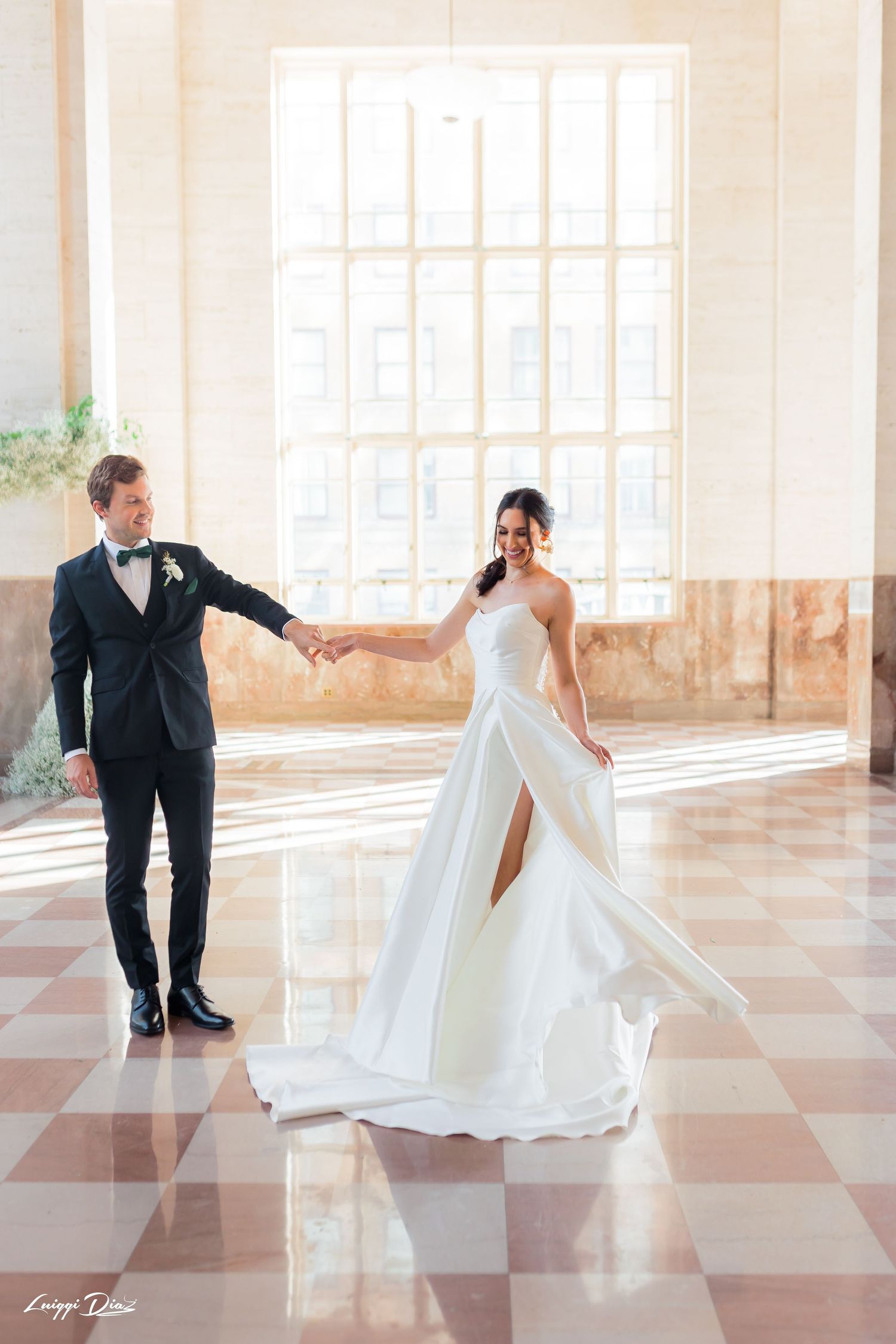 Elegant couple dancing in a bright ballroom with checkered floors.