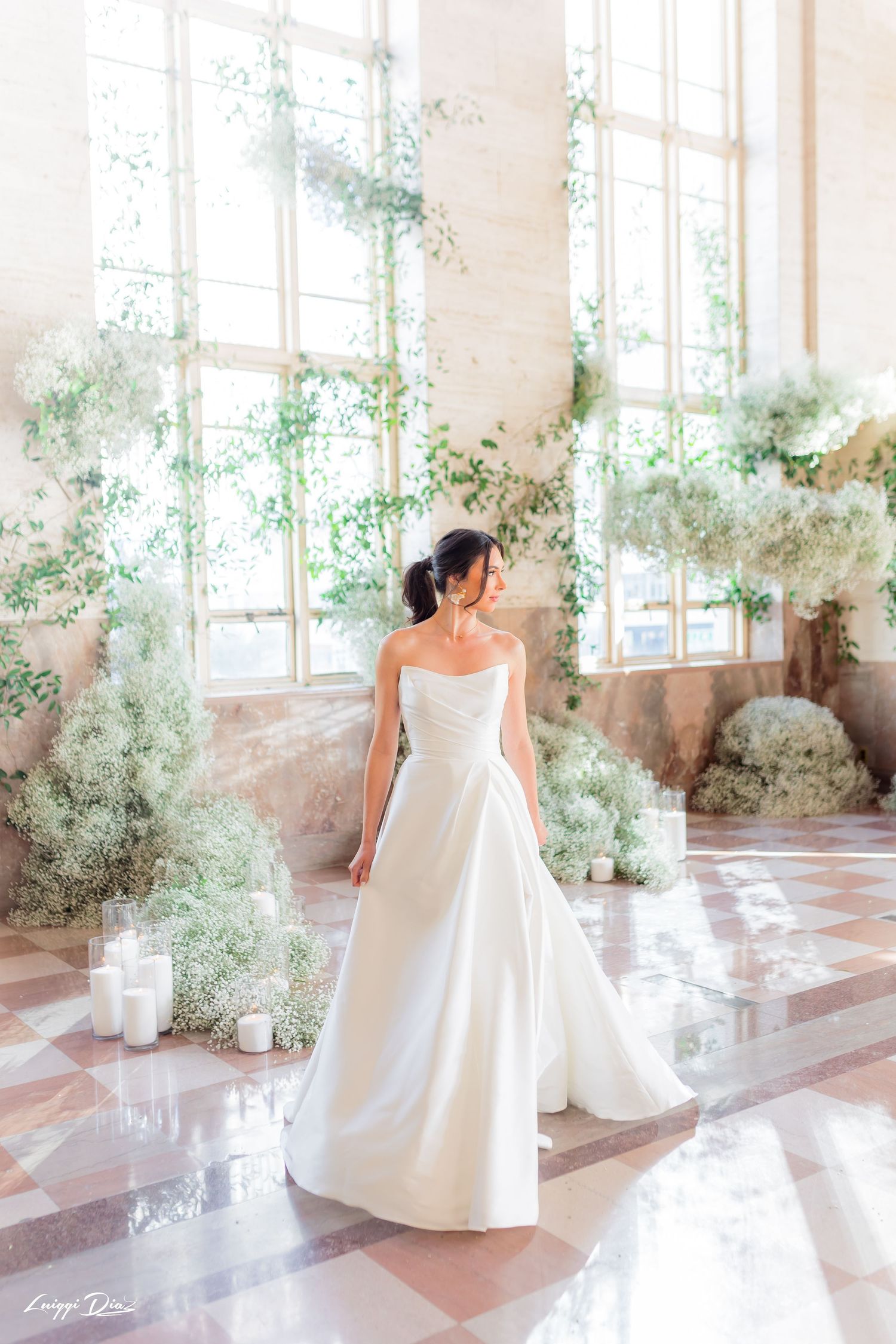 Wedding gown displayed in sunlit room with baby's breath floral decorations.