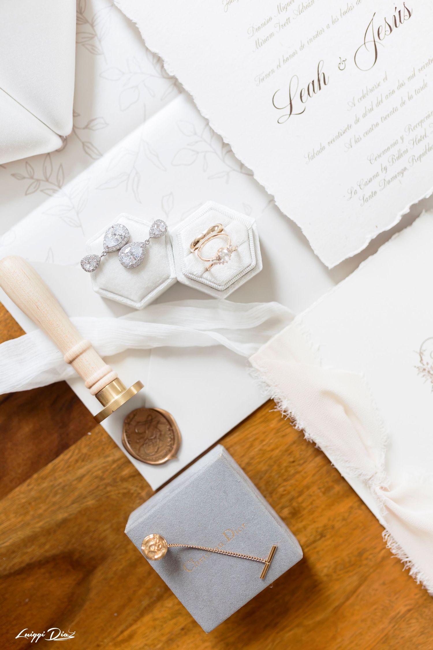 Wedding details with invitation cards, jewelry boxes, and decorative accessories on a wooden surface.