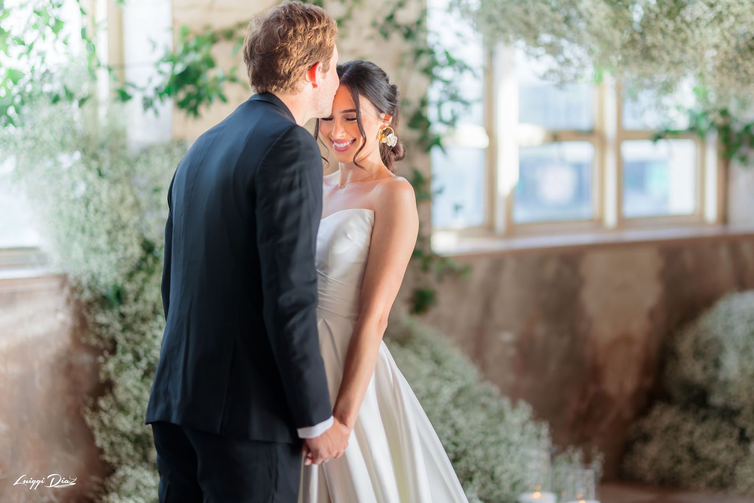 A romantic intimate wedding moment in a sunlit room decorated with greenery.