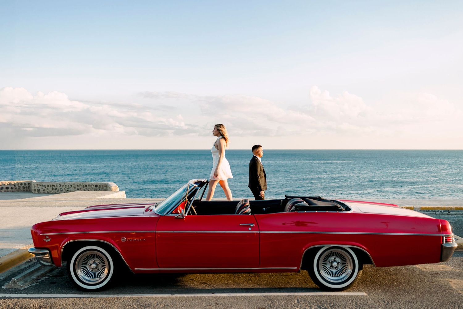 Seaside photoshoot featuring a classic red convertible automobile.