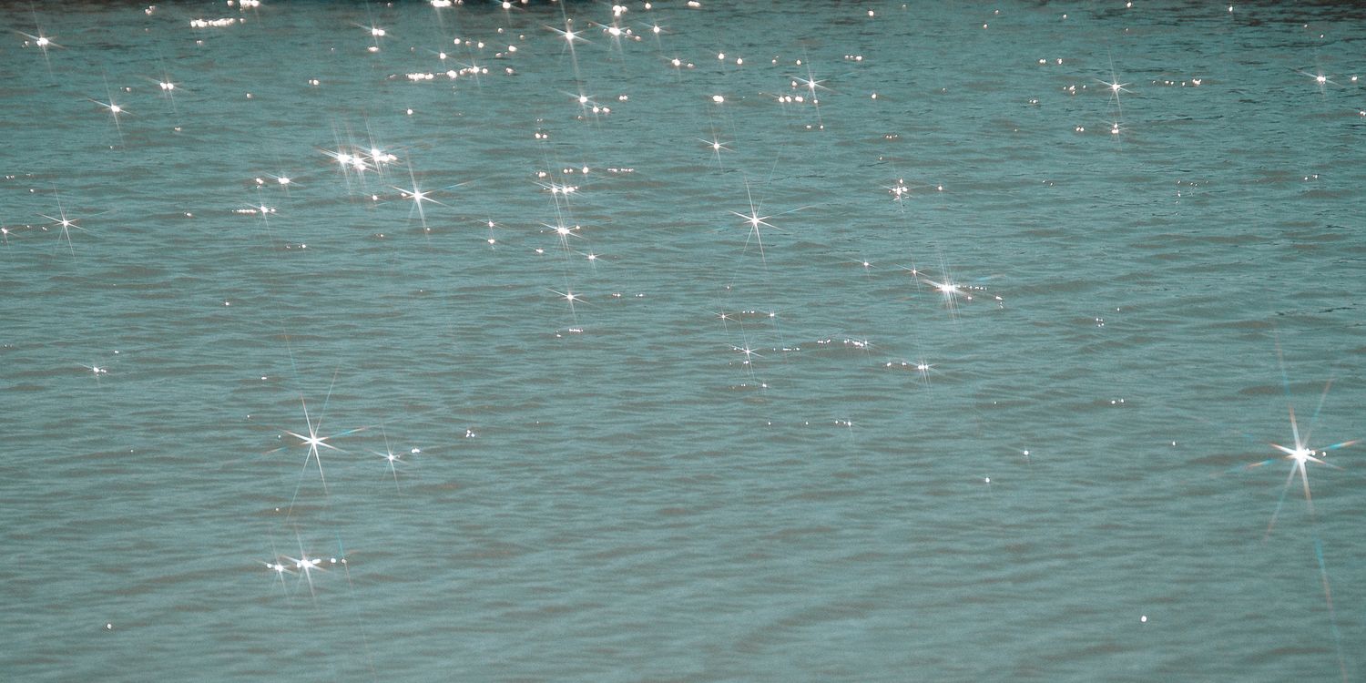 Sparkling turquoise ocean water ripples with sunlight reflections creating a shimmering aquatic surface pattern.