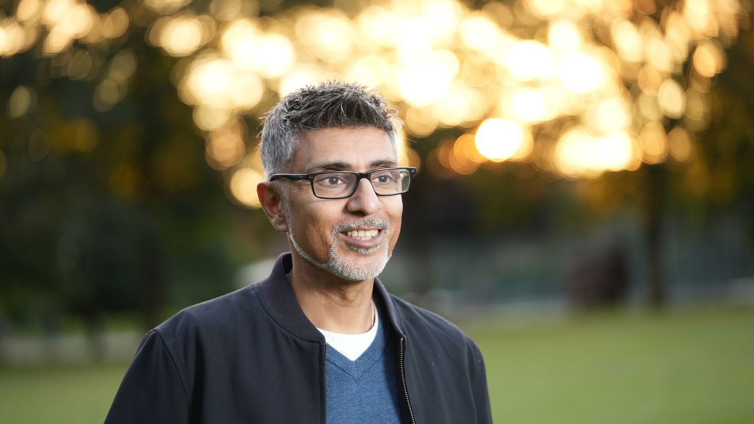 Professional headshot of person in casual attire against sunset background.