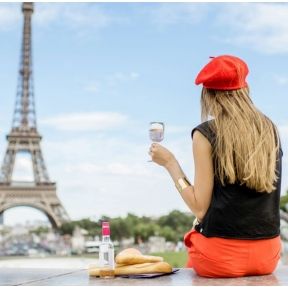 photo d'une femme de dos qui tient un verre de vin devant la tour eiffel
