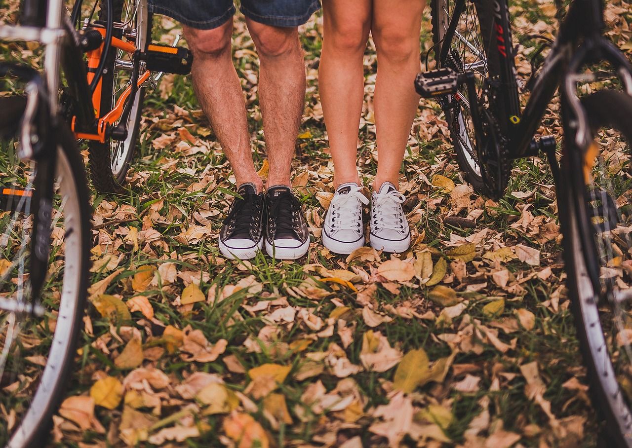 photo des jambes de deux personnes, droites, en baskets, et de roues de vélos