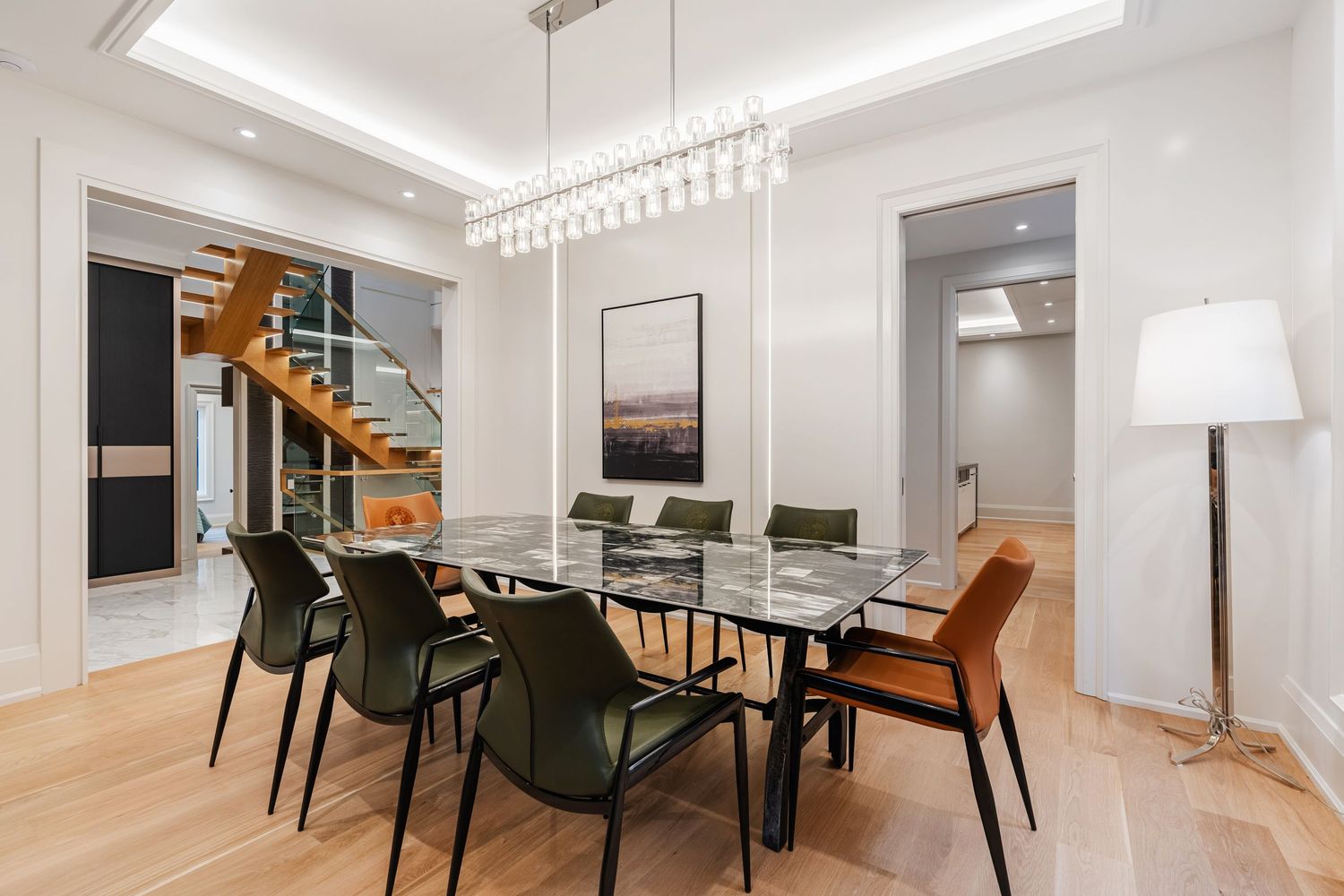 Contemporary dining area featuring glass table, designer chairs, and modern pendant lighting.