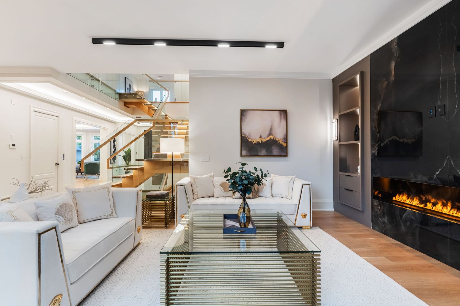 Modern luxury home interior featuring a sleek fireplace, glass railings, and light-filled open concept living spaces.