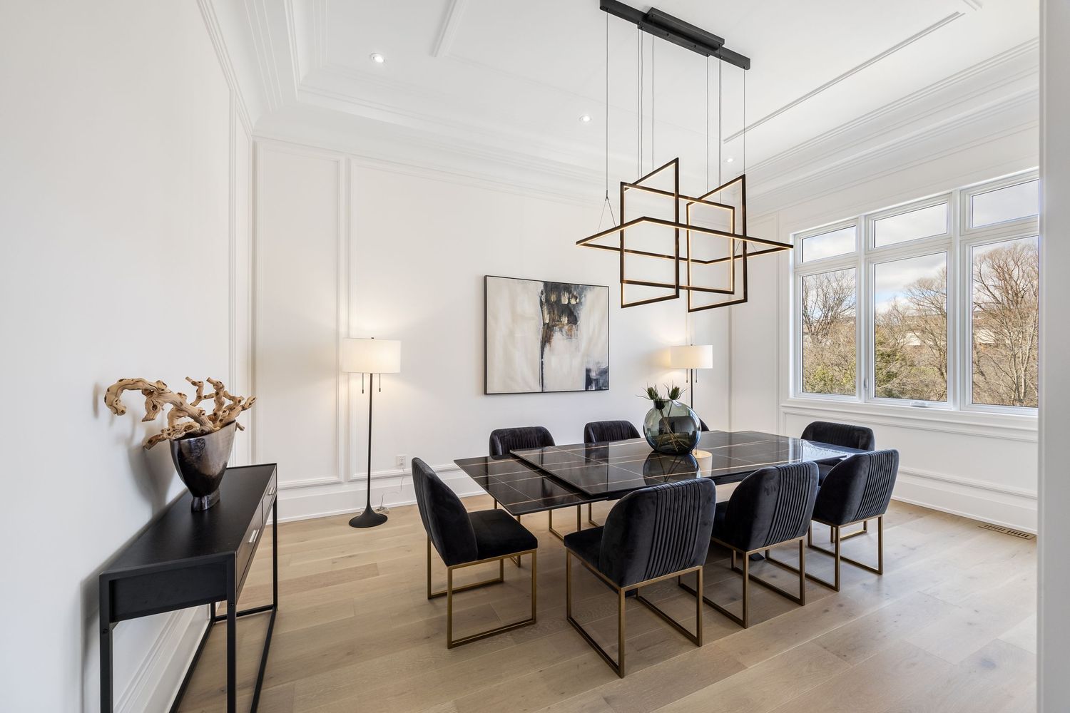 Sophisticated dining room with geometric chandelier, black table, and floor-to-ceiling windows.