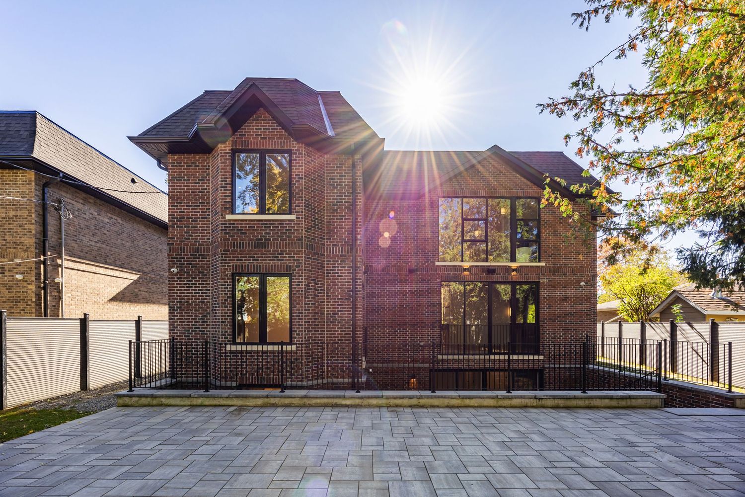 Contemporary home facade with large windows and wooden deck capturing golden sunset light.