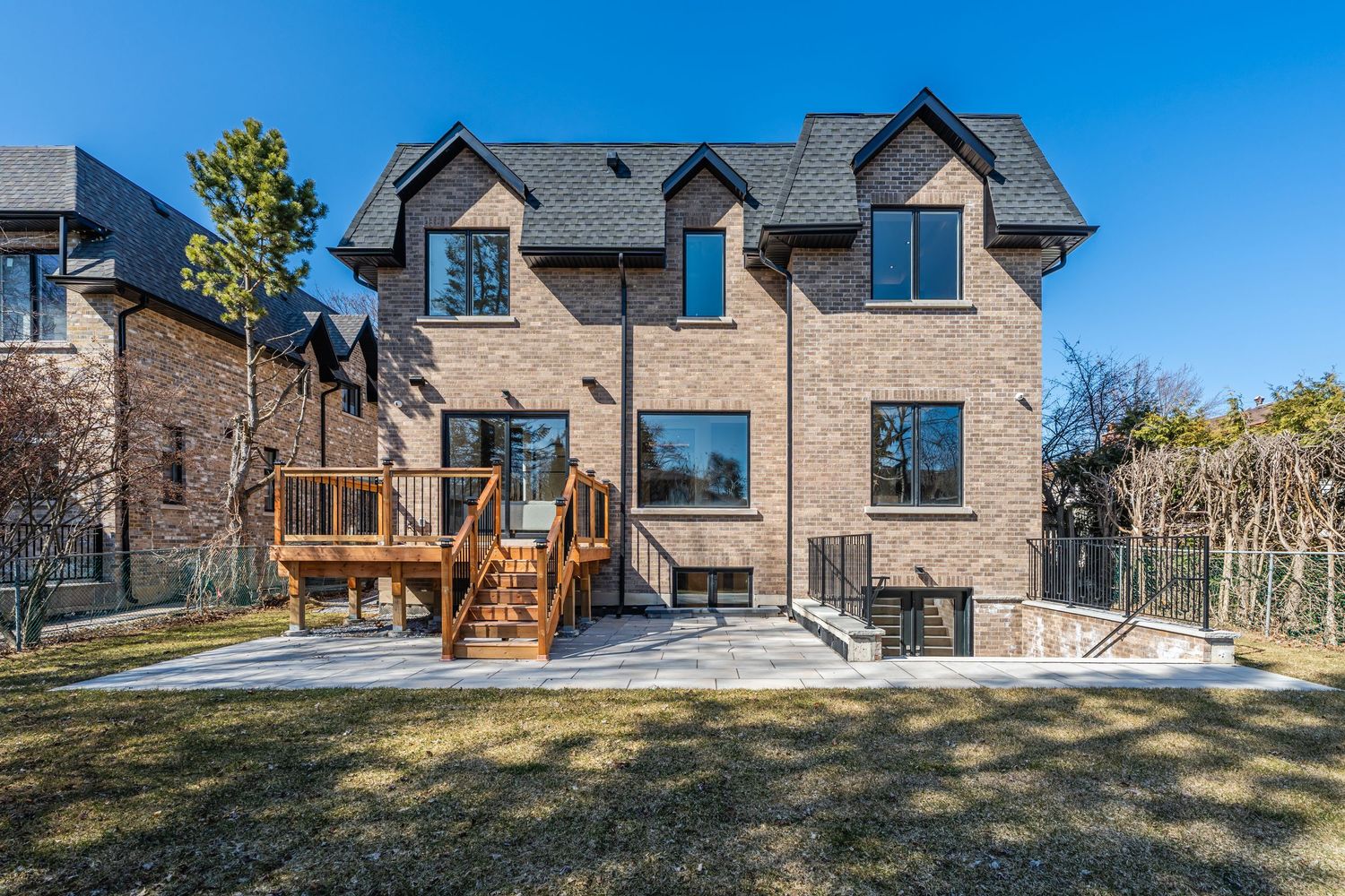 Panoramic view of upscale modern homes with stone exteriors and large windows on a hillside property.