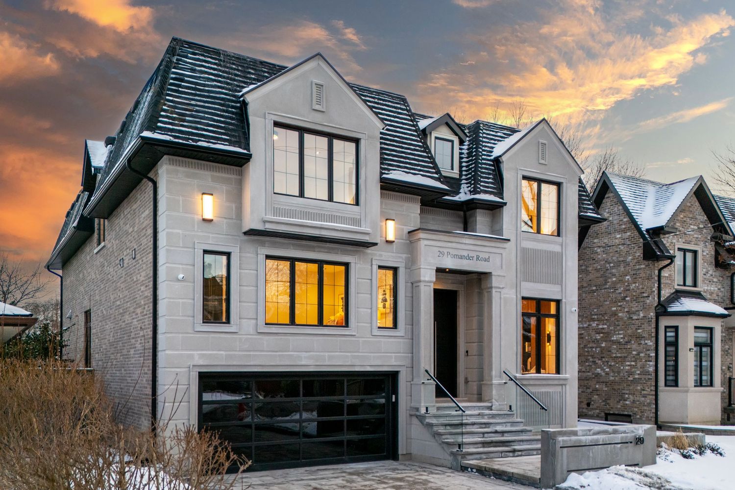 Luxurious modern house with dramatic lighting and three-car garage during winter sunset.