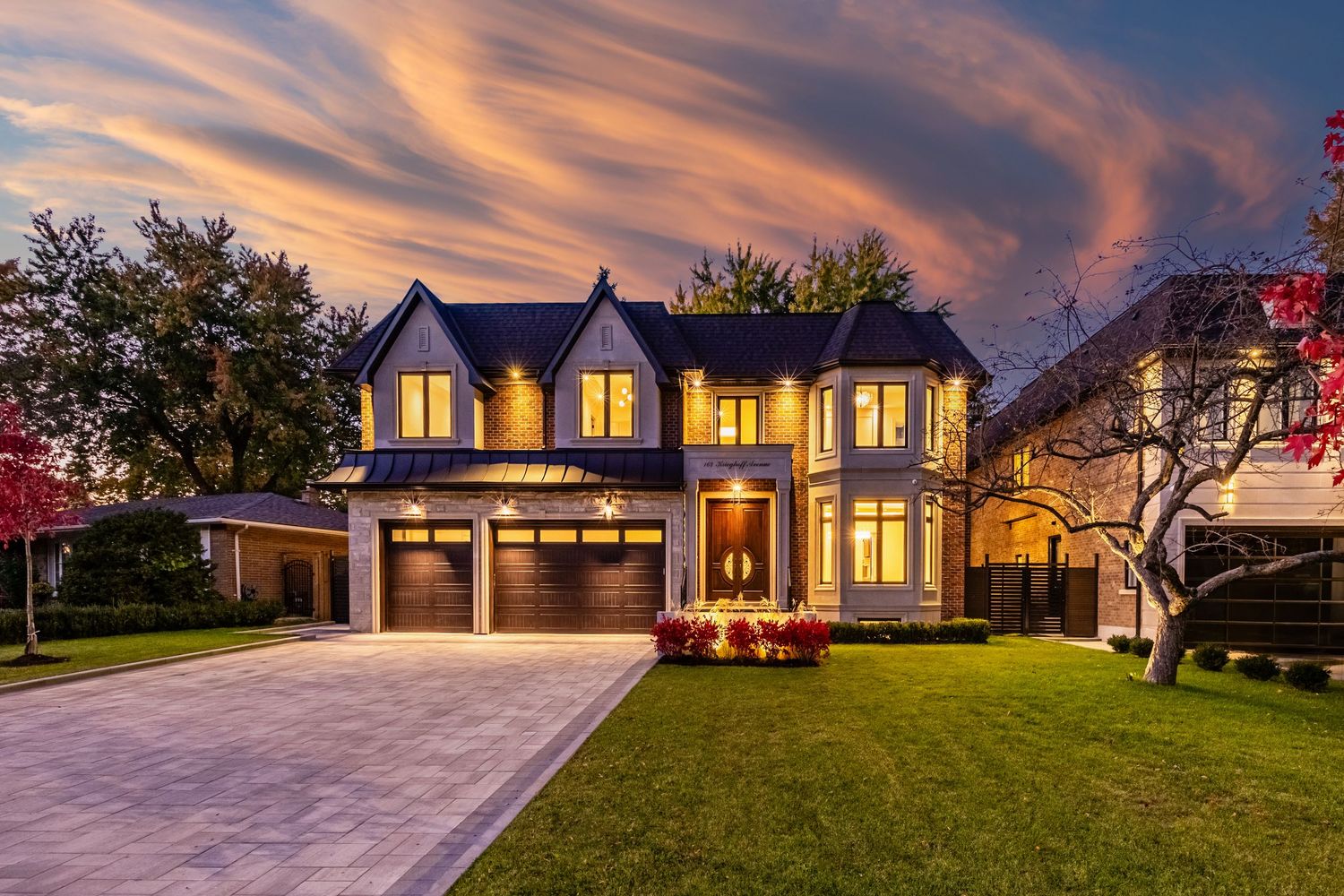 Contemporary two-story home with double garage illuminated at dusk under dramatic sunset sky.