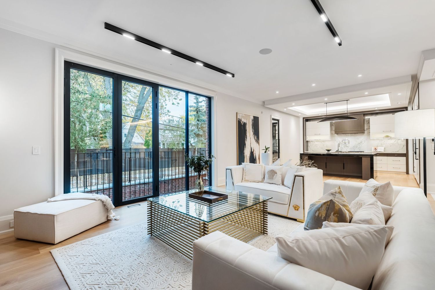 Expansive living room with large windows, white walls, and comfortable seating arranged around natural lighting.