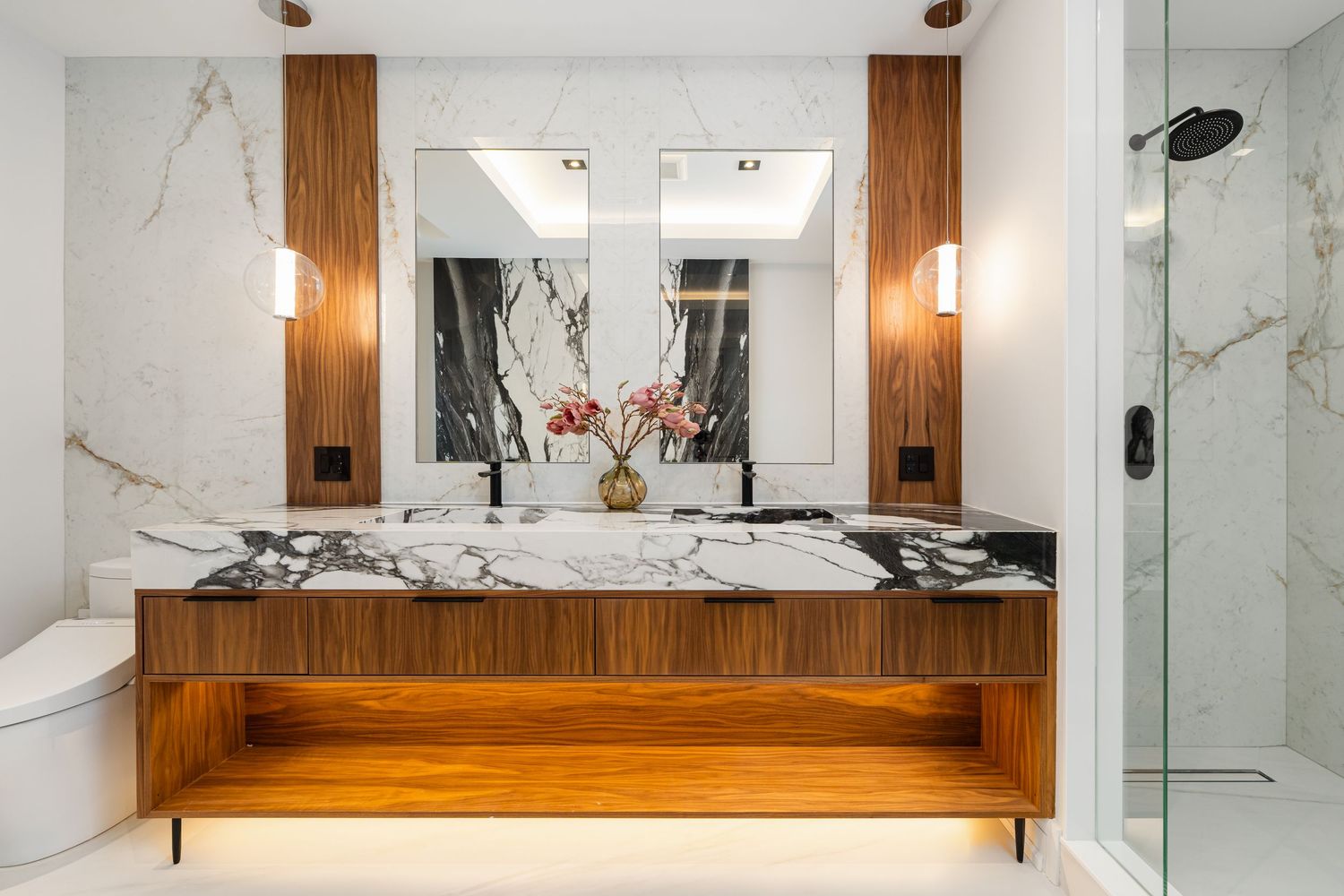 Upscale bathroom featuring wooden accents, marble walls, and modern fixtures.