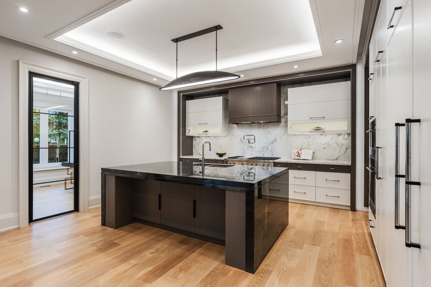 Spacious kitchen with white cabinetry, dark accent island, and high-end stainless steel appliances.