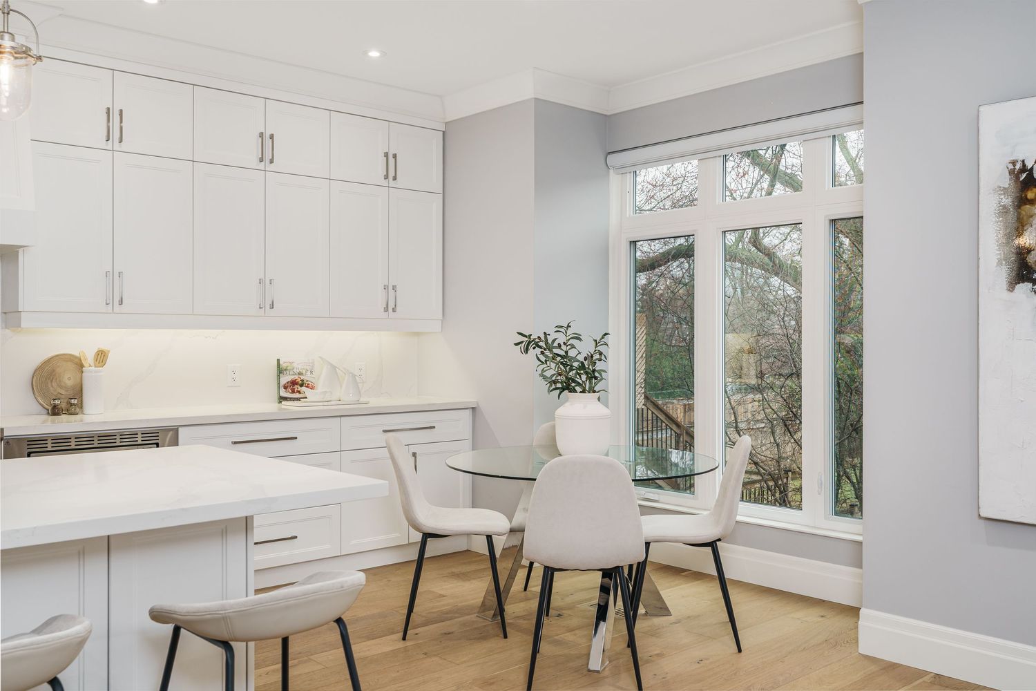 Bright modern kitchen with white cabinets, floating shelves, and large windows showcasing natural light.