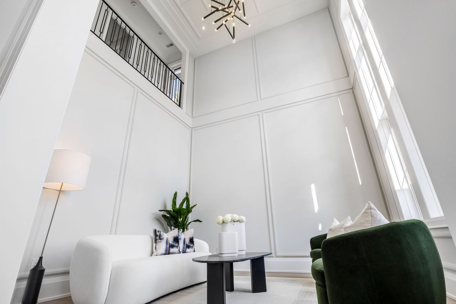 Modern white living room with high ceilings, contemporary furniture and natural light.