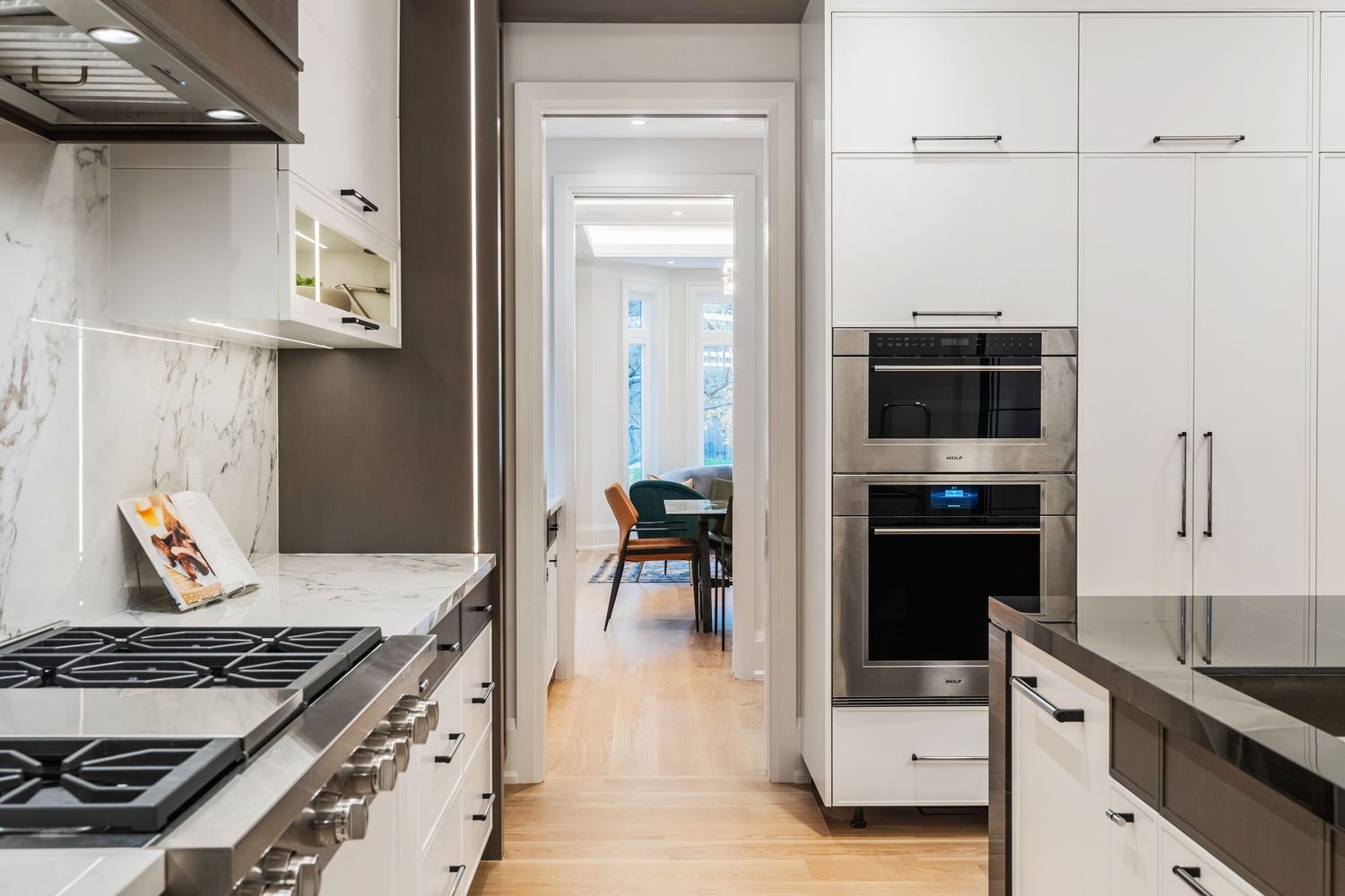 White kitchen with gas range, built-in appliances, and extensive cabinet storage space.