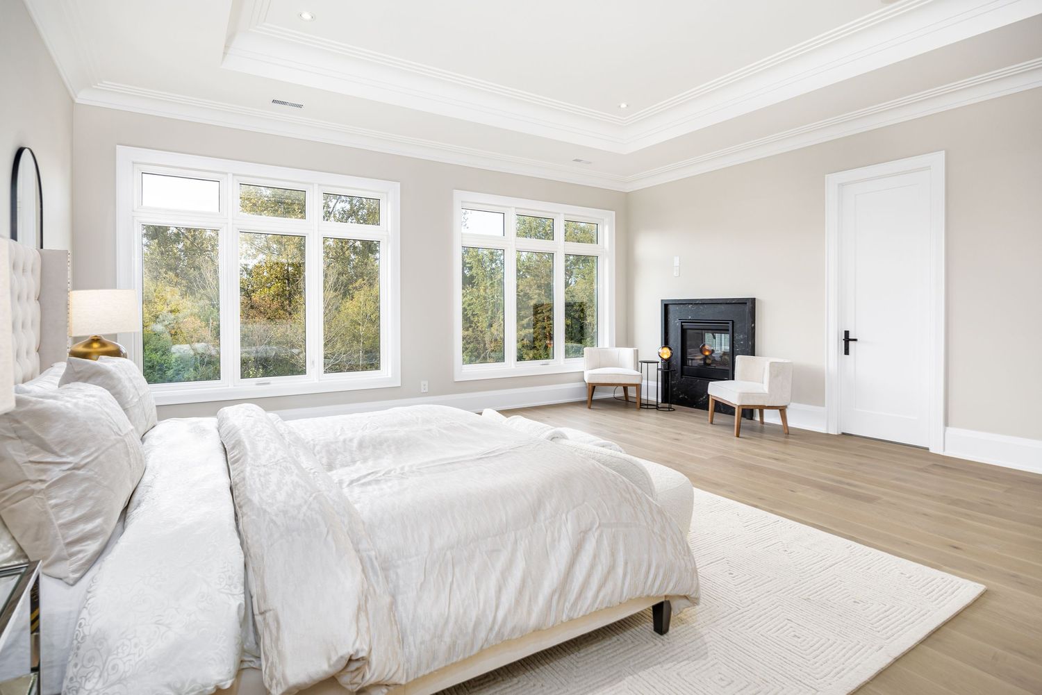 Bright white bedroom with large windows and hardwood flooring in modern design.