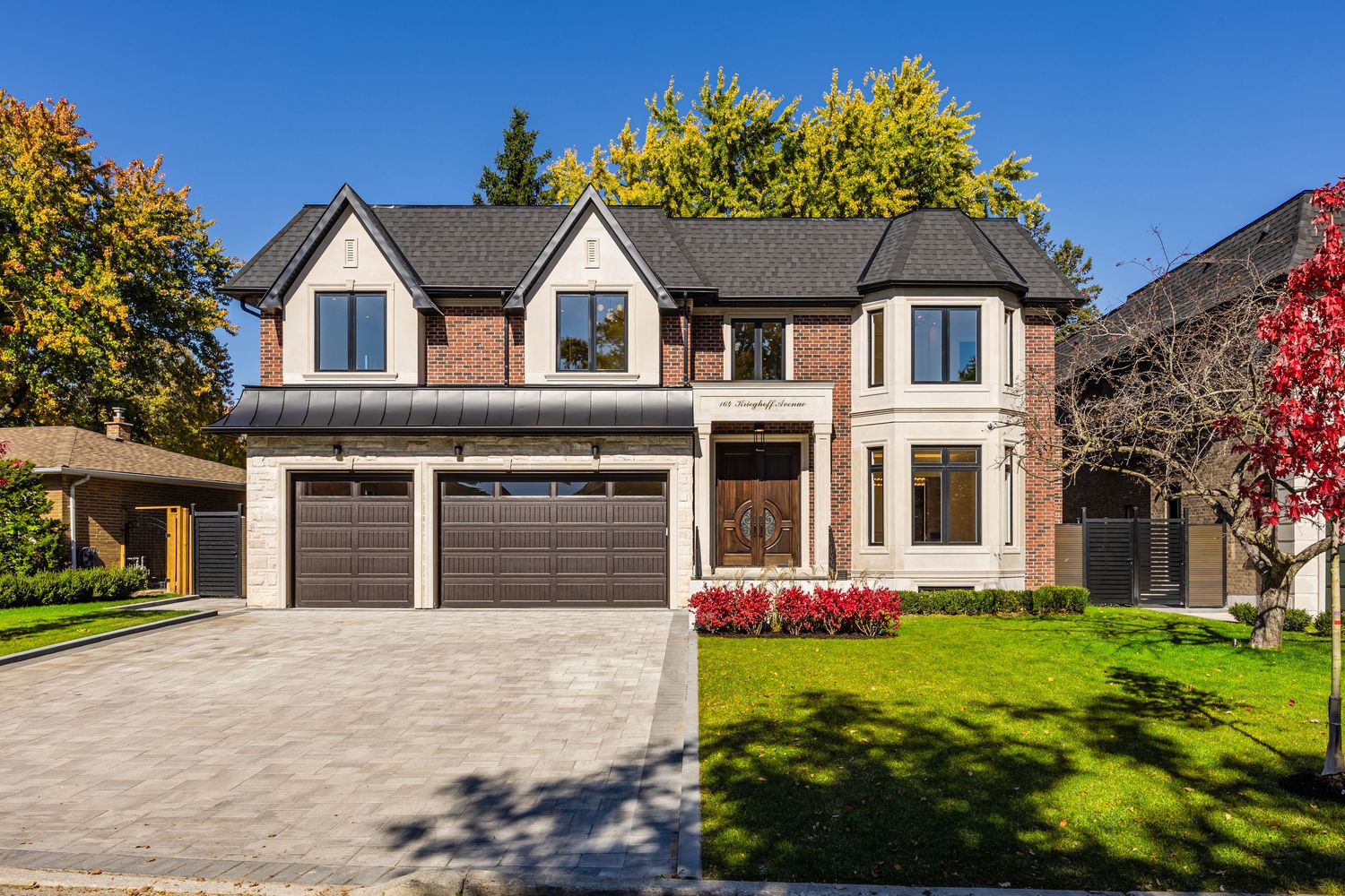 Wide angle view of luxury home exterior with triple car garage and manicured landscaping.