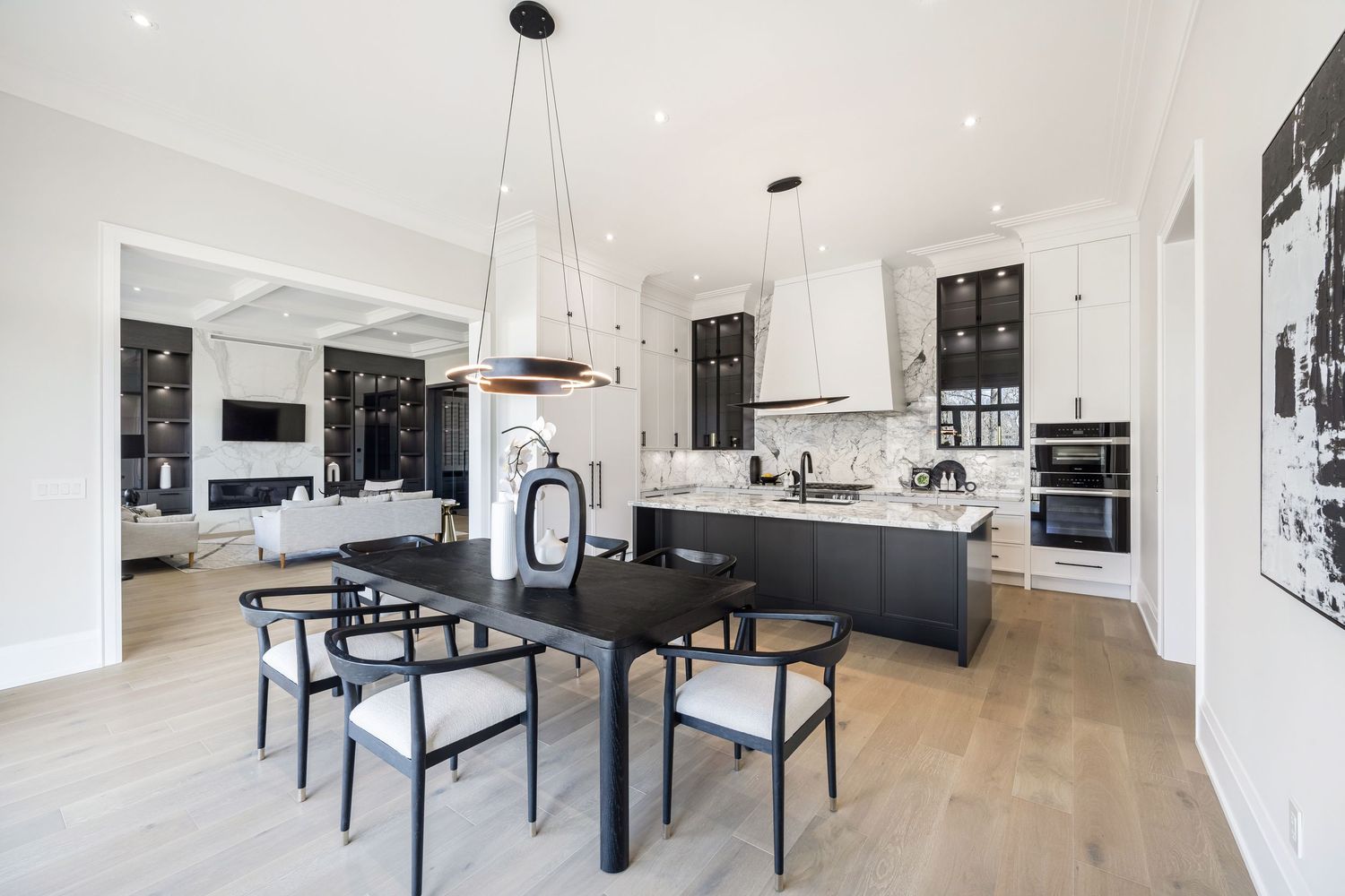 Contemporary open concept kitchen and dining area with black dining set and pendant lighting.