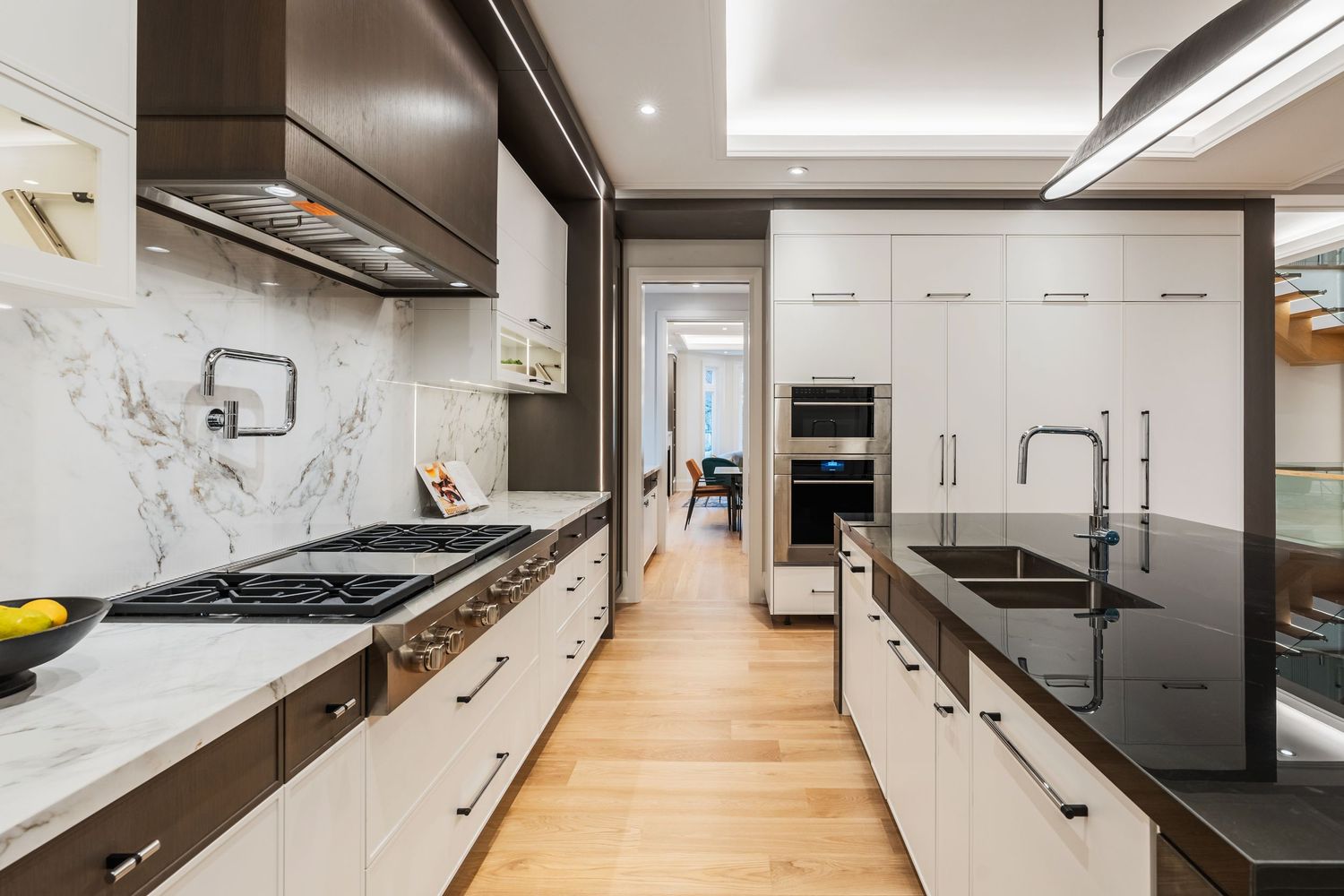 Modern kitchen design with integrated appliances, marble backsplash, and sleek hardware finishes.