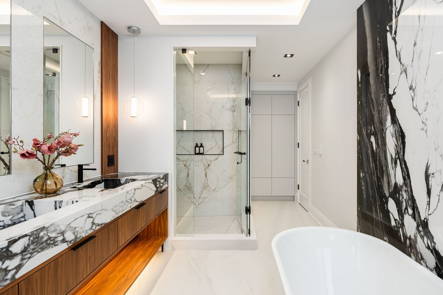 Spacious bathroom with marble walls, skylight, and warm wood accents.