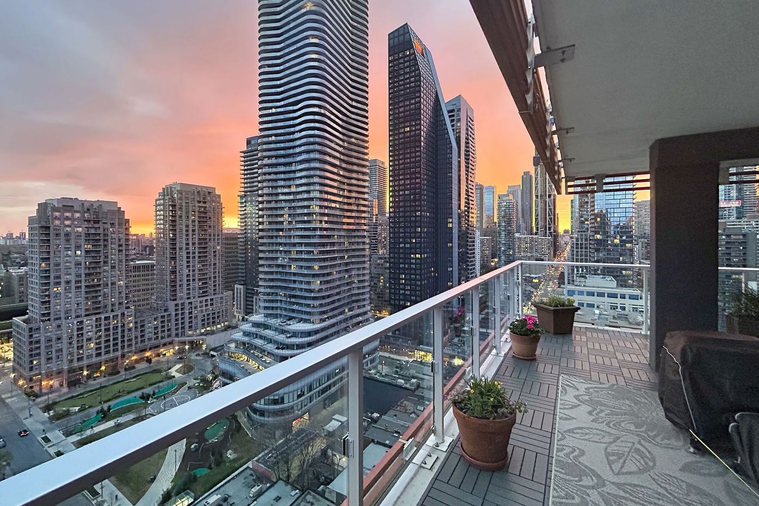 A stunning cityscape view of modern skyscrapers and high-rise buildings from a balcony during sunset in downtown toronto.
