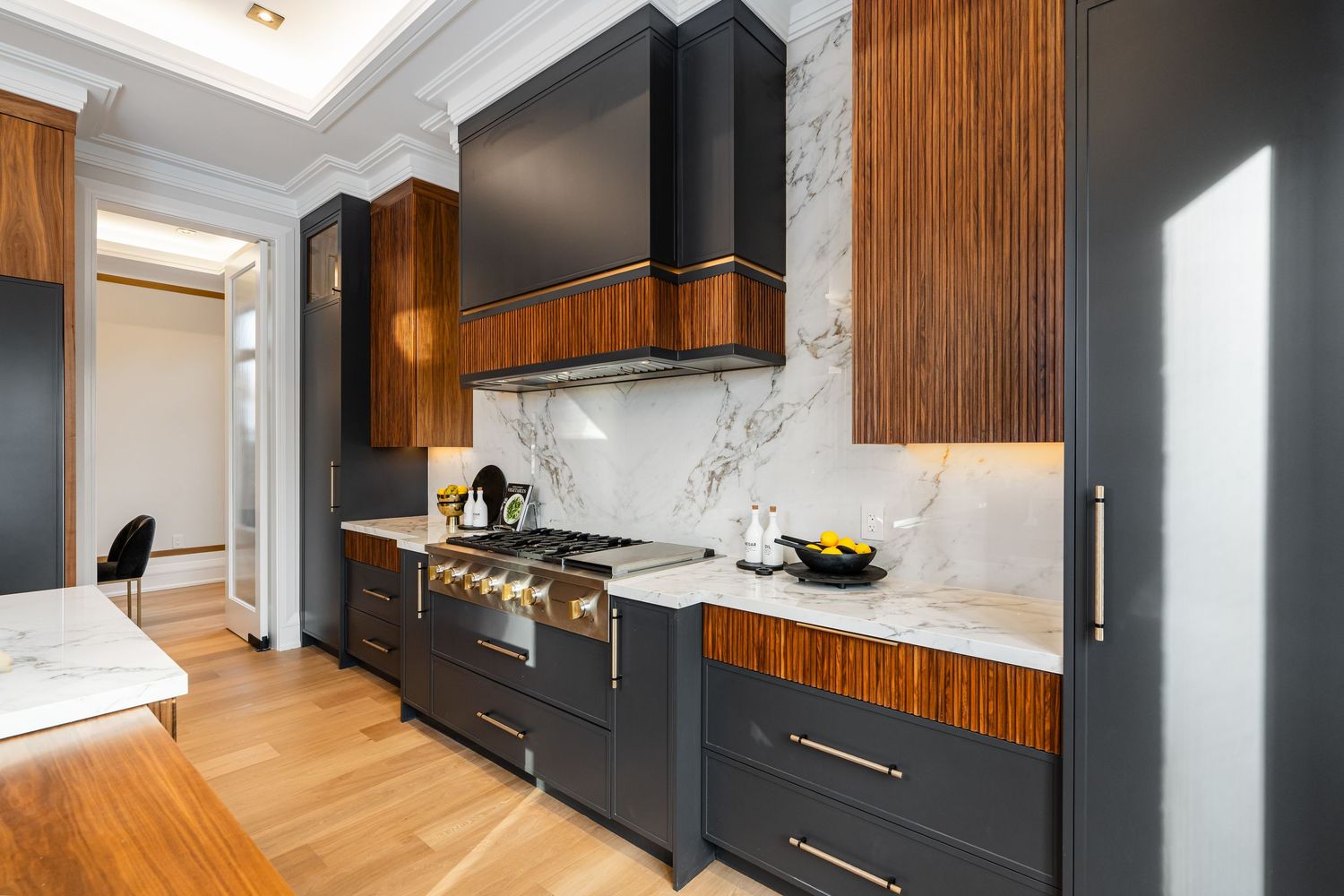 Elegant kitchen with marble backsplash, black cabinetry, and warm wood accents against white walls.