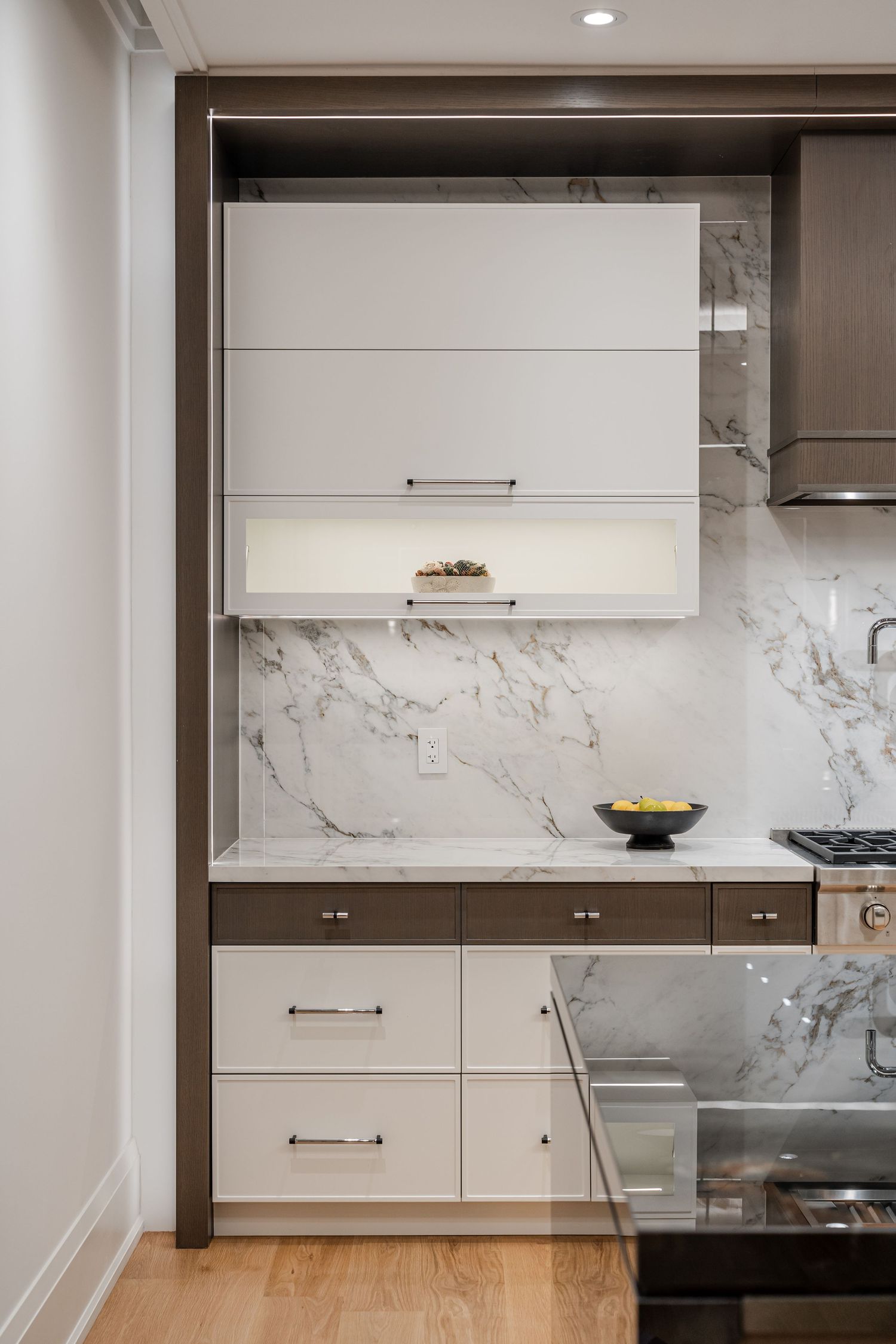 Modern white kitchen cabinets with marble backsplash and wooden accents showcase sleek contemporary design.