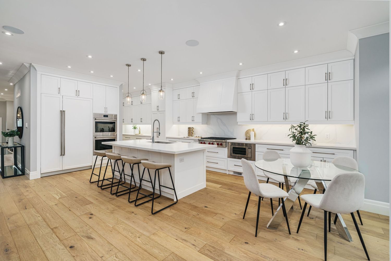Modern white kitchen design with light hardwood floors, pendant lights, and sleek cabinetry spanning across multiple views.