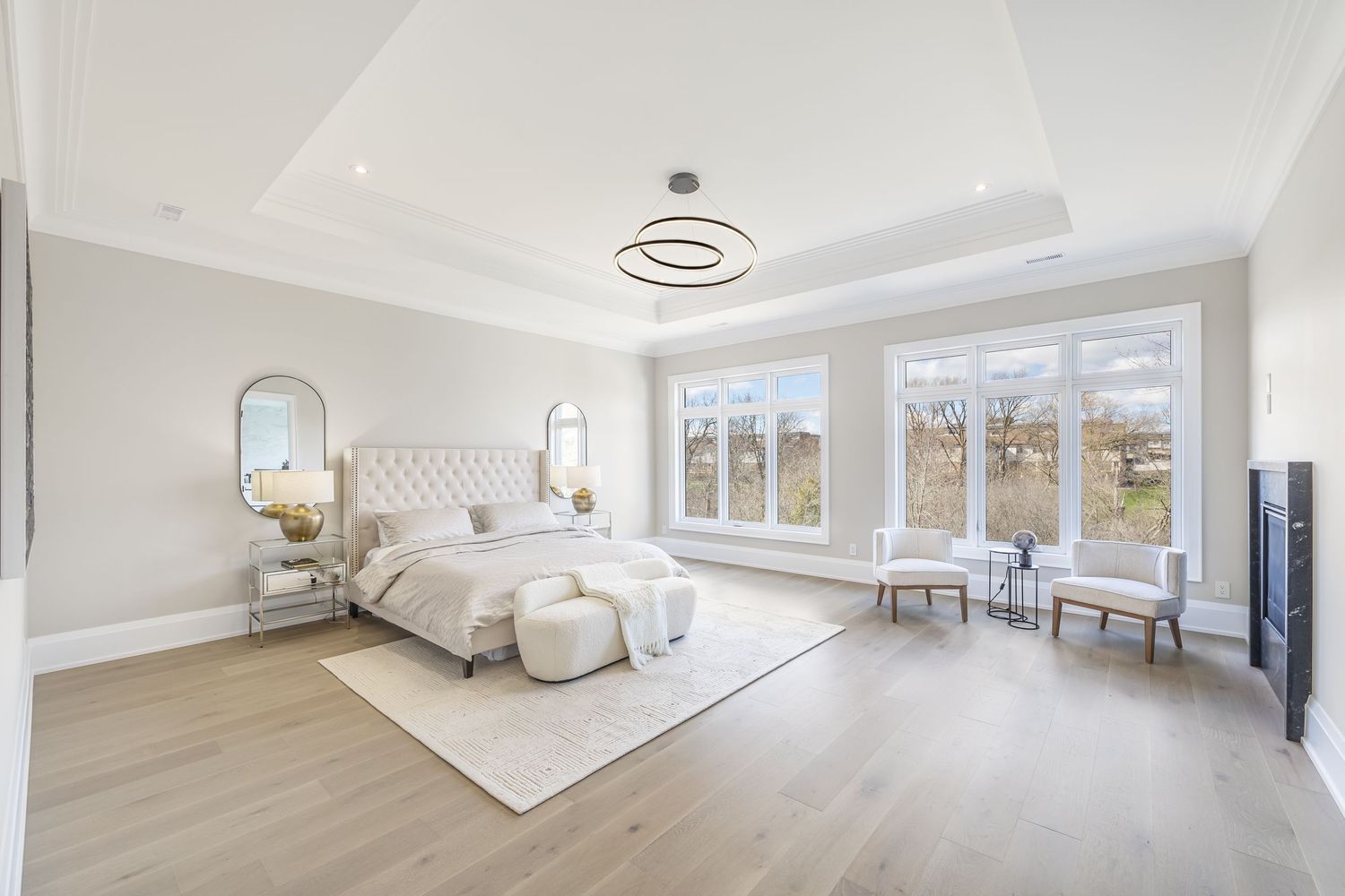 Luxurious master bedroom featuring white decor, arched mirrors, and hardwood flooring with panoramic windows.