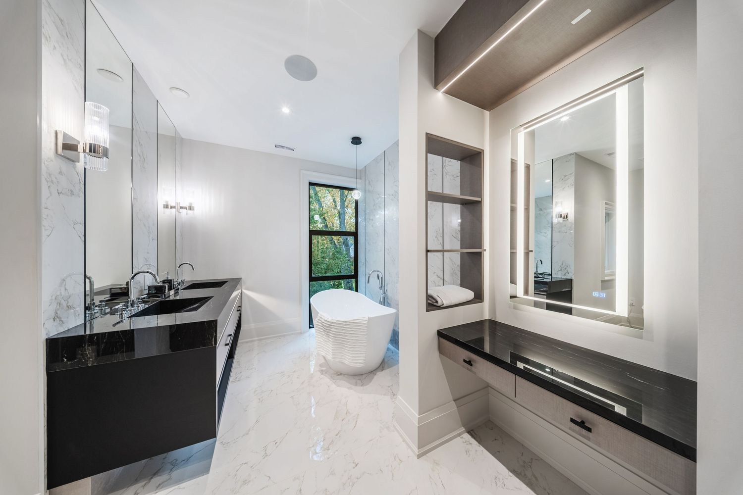 Luxurious bathroom with freestanding tub, black vanity, and floor-to-ceiling mirrors.