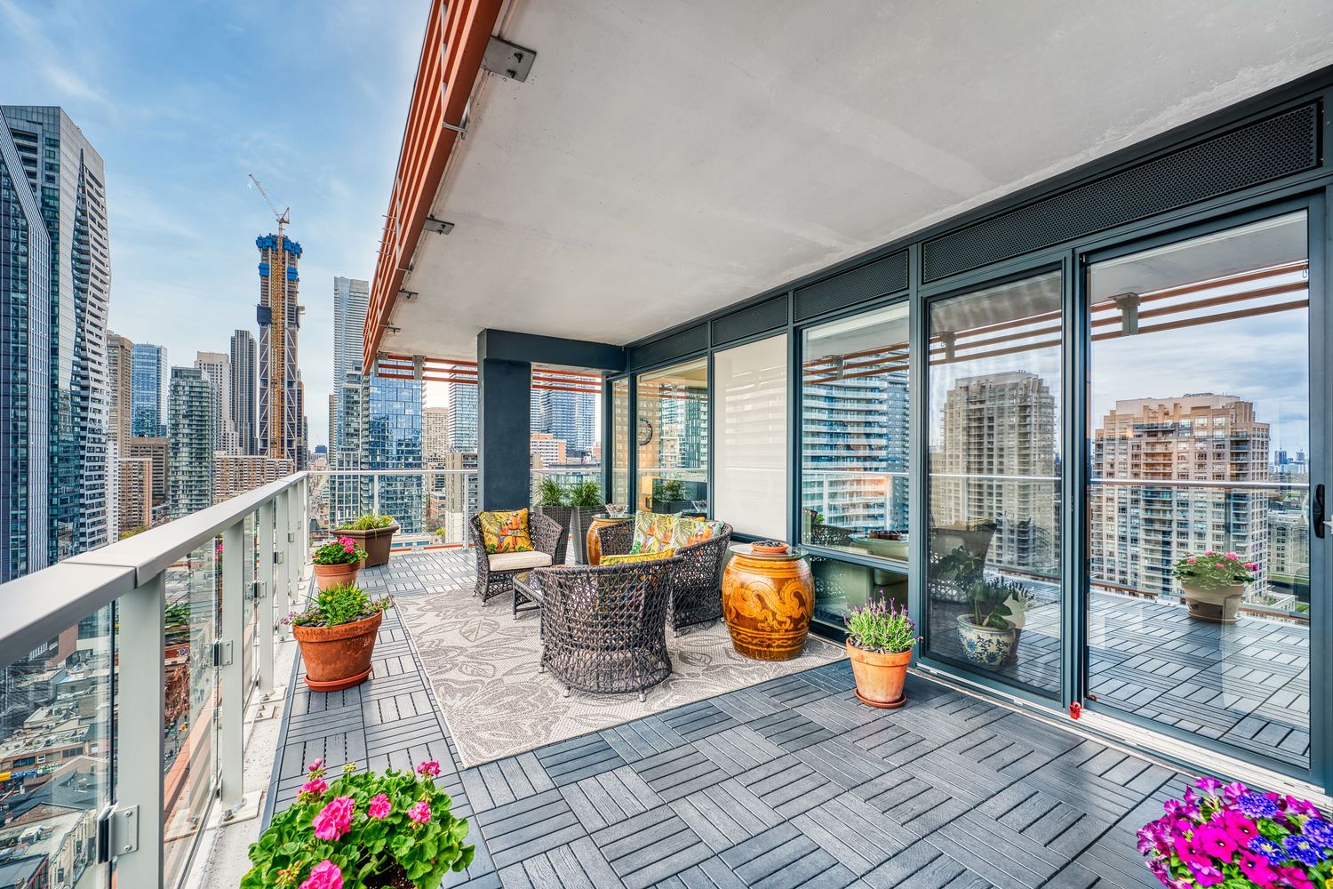 Modern high-rise balcony with outdoor furniture and potted flowers overlooking Chicago's downtown skyline view.