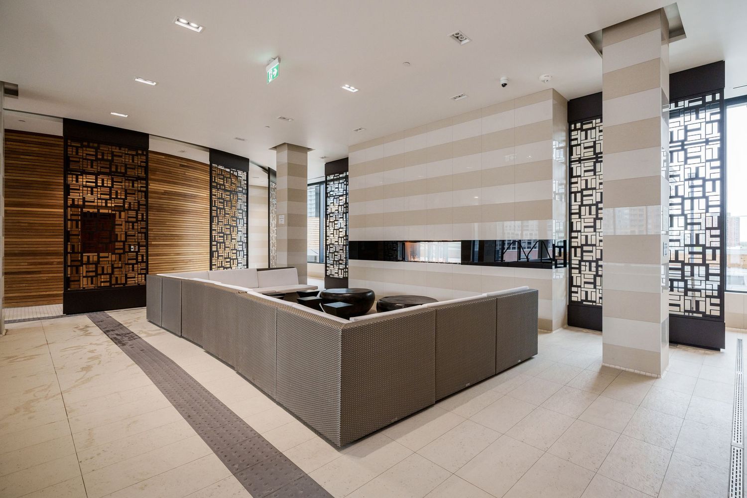 Modern luxury lobby interior with geometric wall patterns, stone floors and a sleek gray seating area with built-in sofa.
