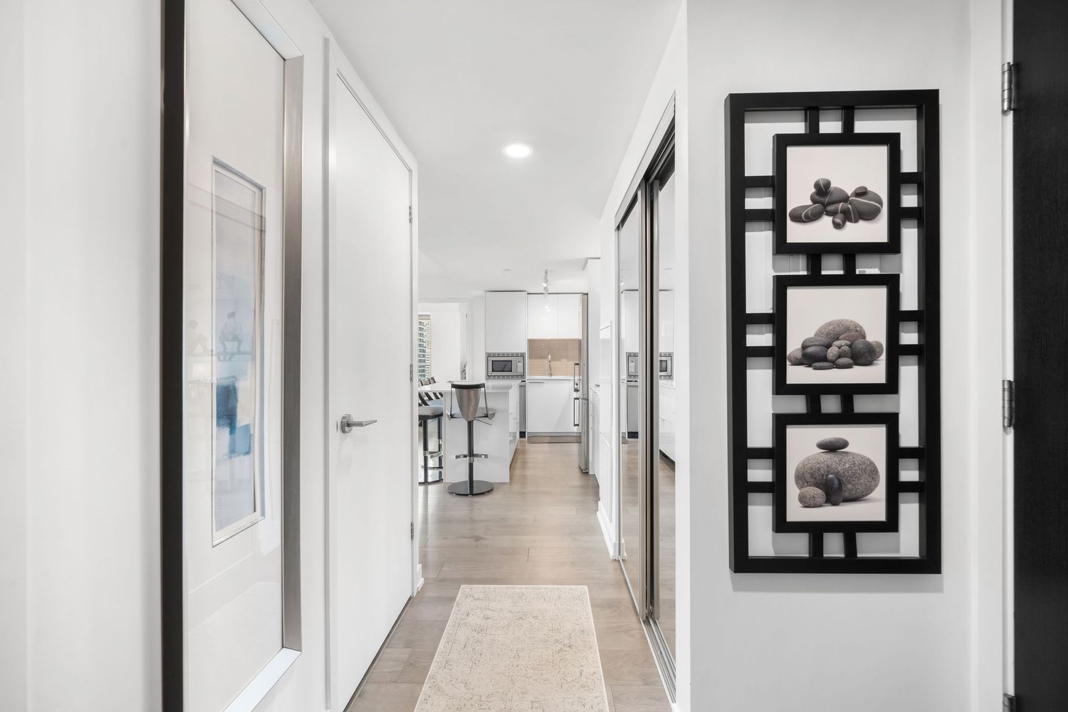 Minimalist white hallway with black geometric wall art and recessed lighting creating a modern gallery-like atmosphere.