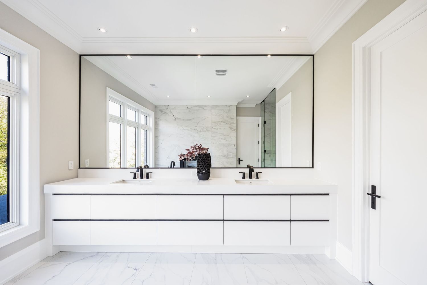 Modern white bathroom interior with large mirror and minimalist fixtures.