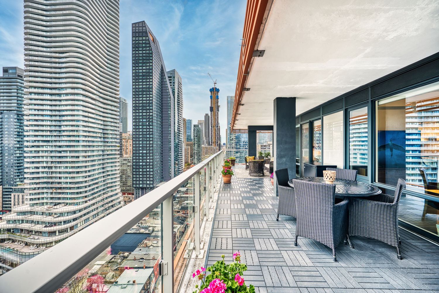 Modern high-rise balcony with outdoor furniture overlooking downtown Chicago skyscrapers on a sunny day.