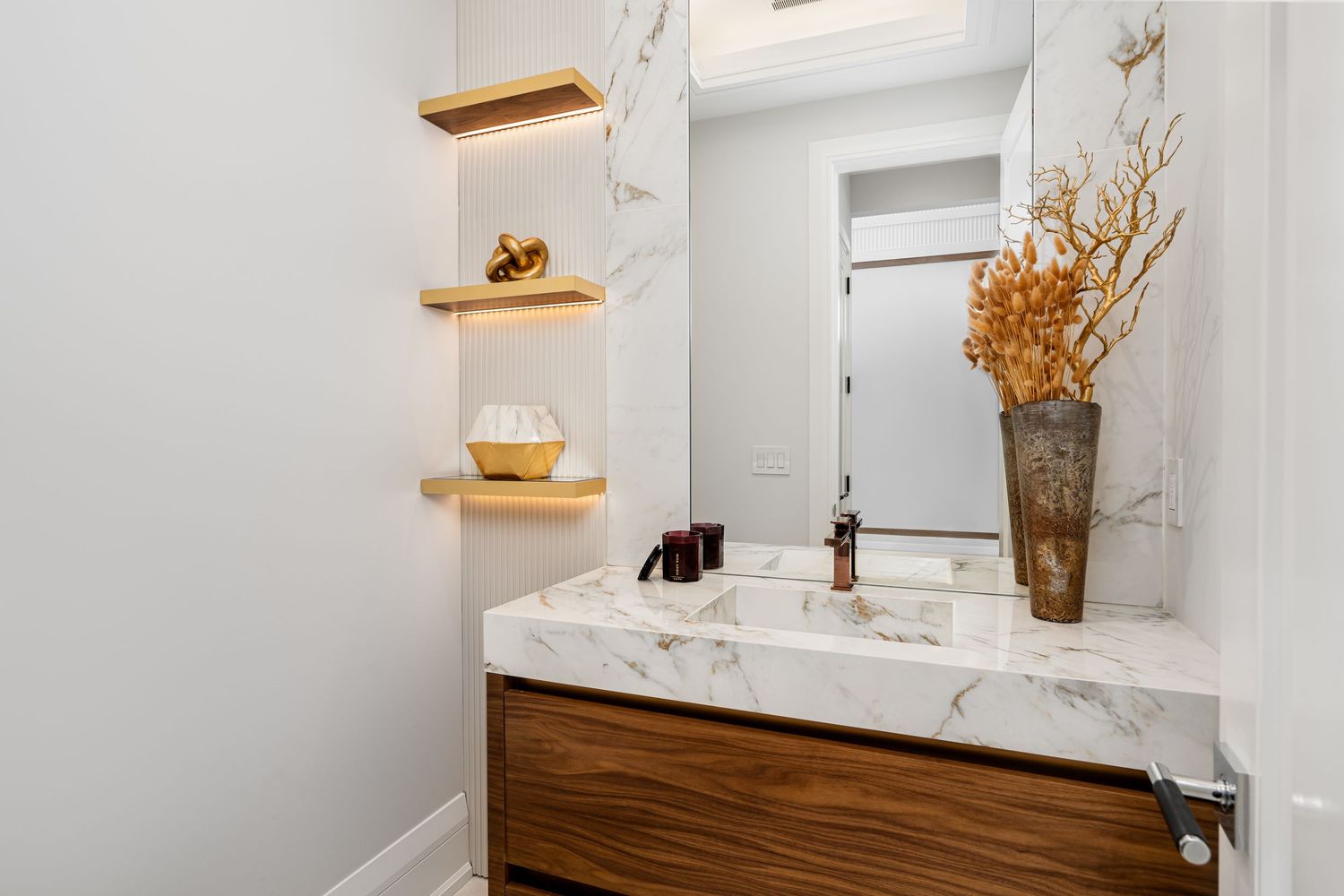 Contemporary white marble bathroom with wooden vanity and decorative accents.
