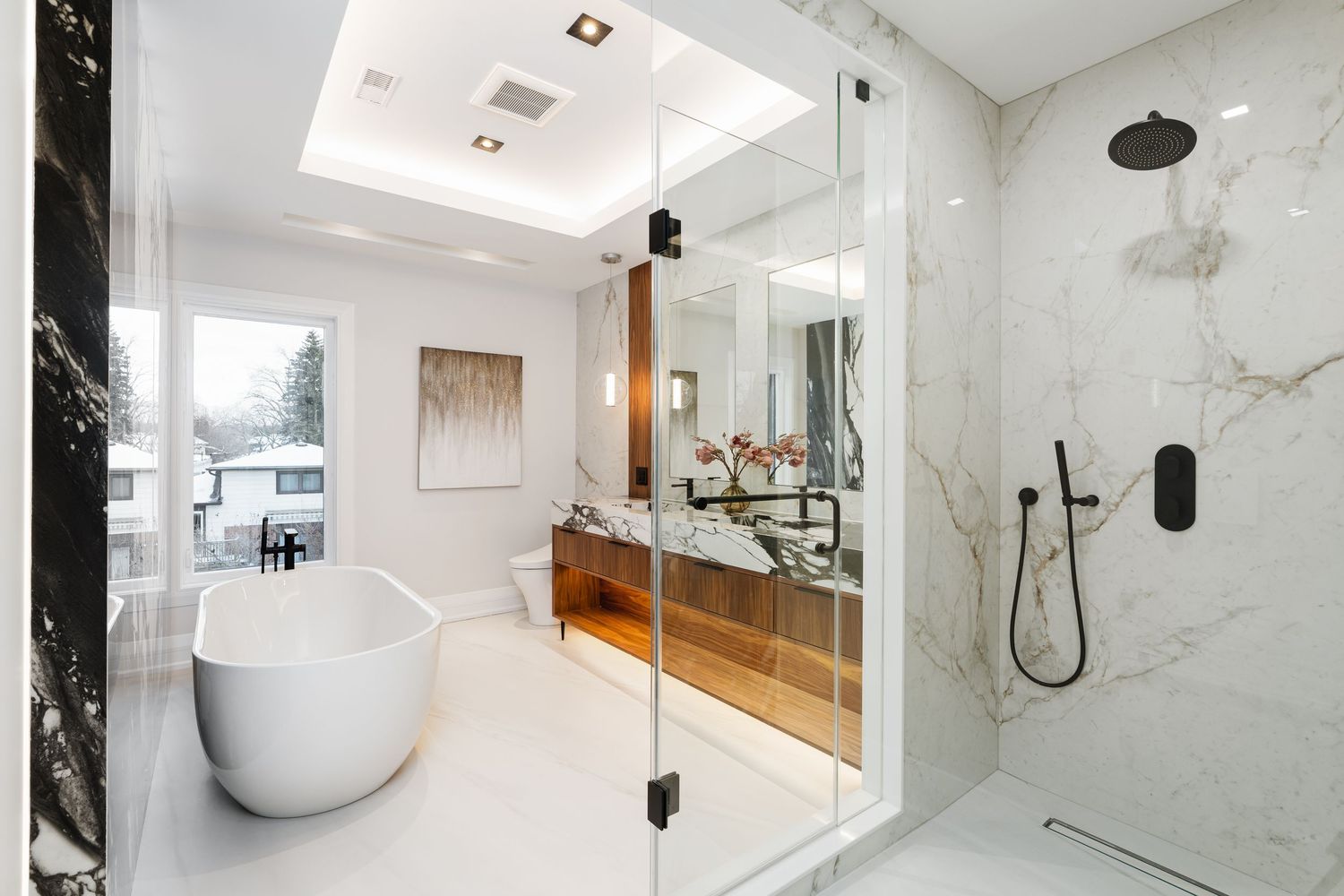 Marble bathroom with freestanding tub, glass shower enclosure, and skylight.