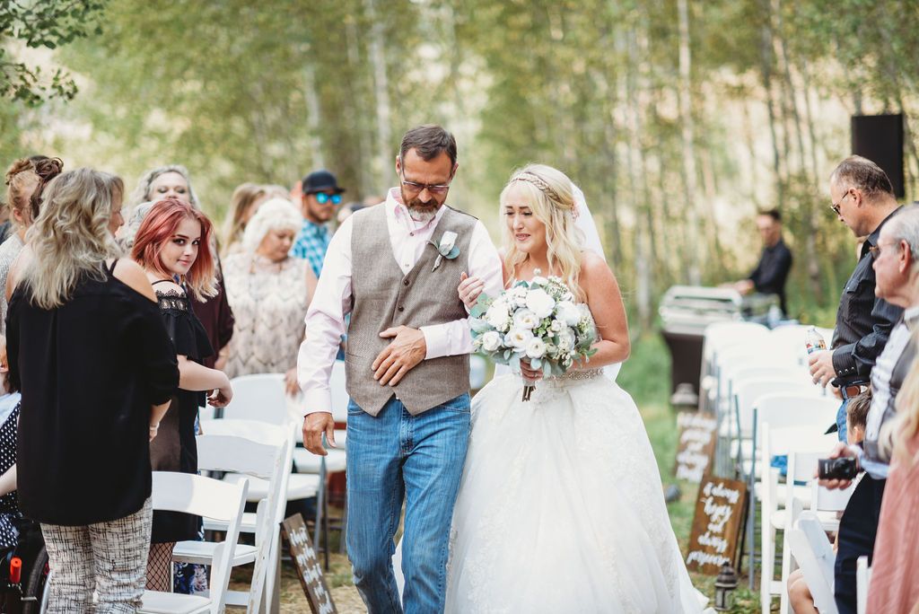 Outdoor wedding ceremony in a bamboo forest with white chairs and guests lining the aisle.