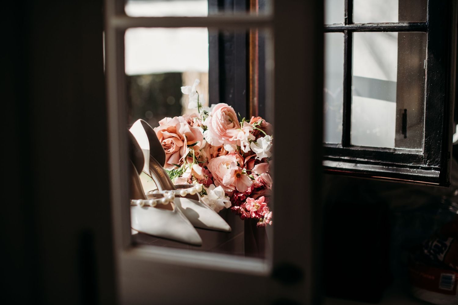 Pink roses in a vase by a window create a romantic indoor scene with soft natural lighting.